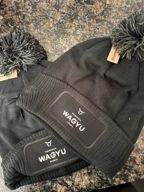 Black Snowdonia Wagyu branded pom-pom beanie, a unique Welsh Christmas gift for farmers and food lovers.
