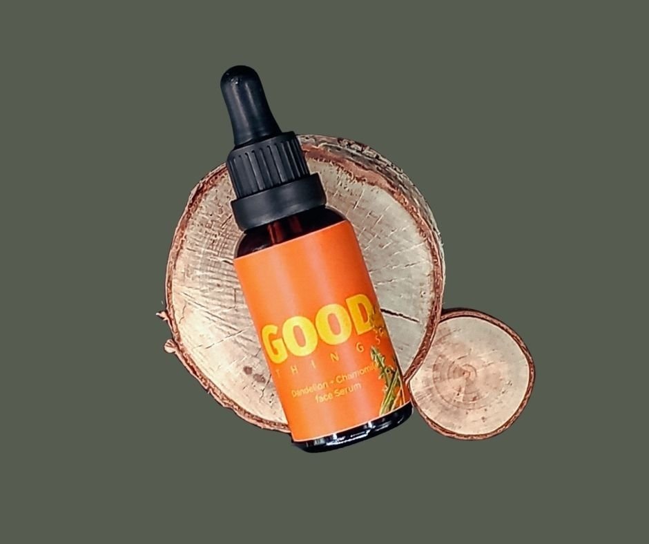 Natural face serum with dandelion and chamomile, displayed on a wooden tray .