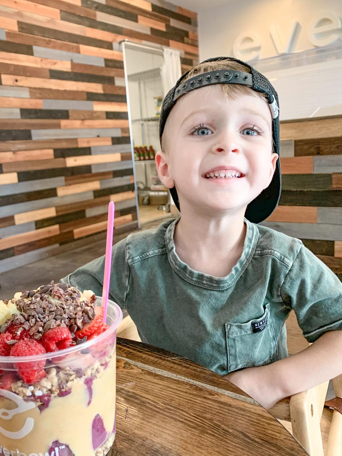 Little boy eating acai bowl with a big smile