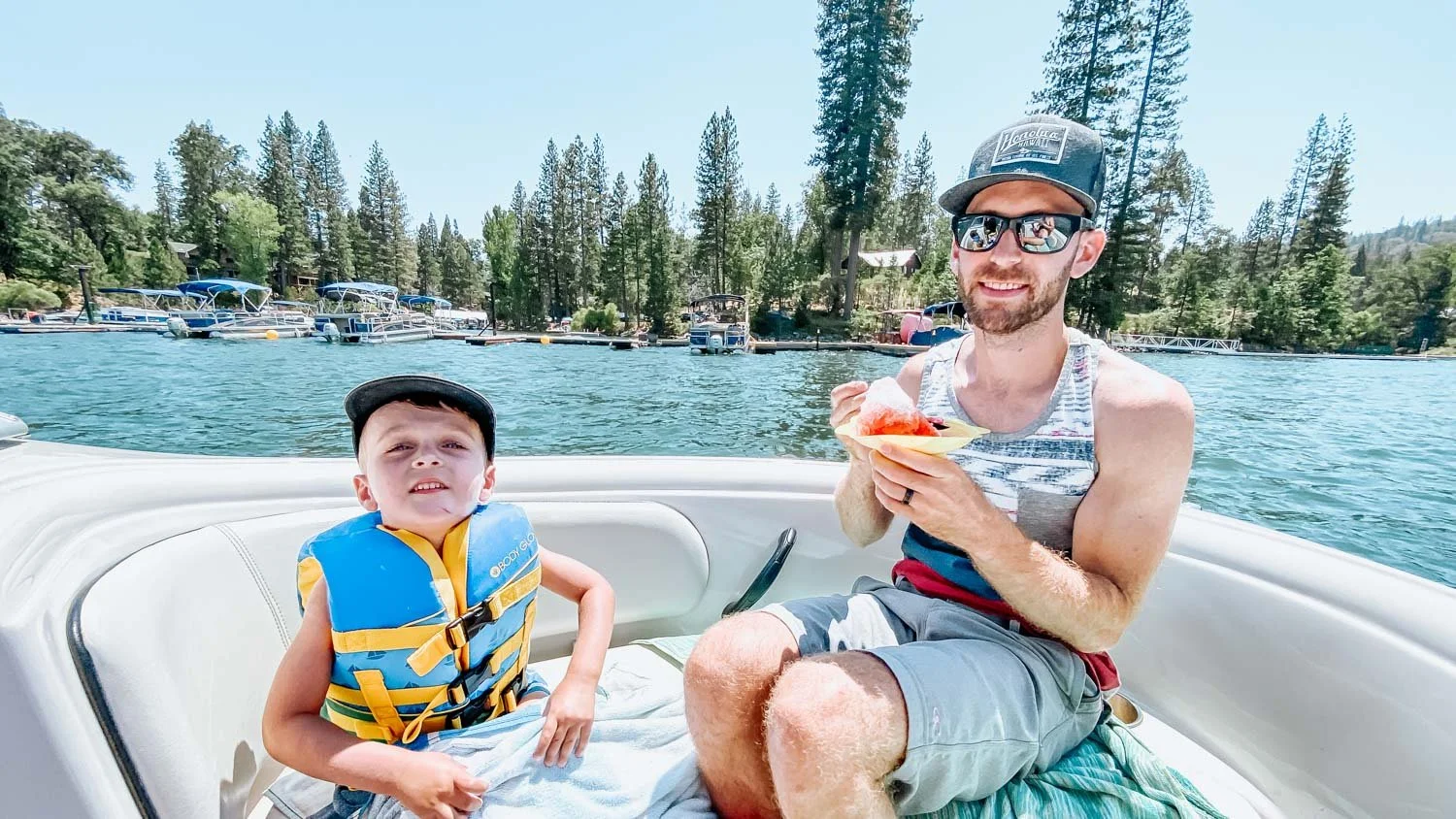father and son eating shaved ice on front of boat