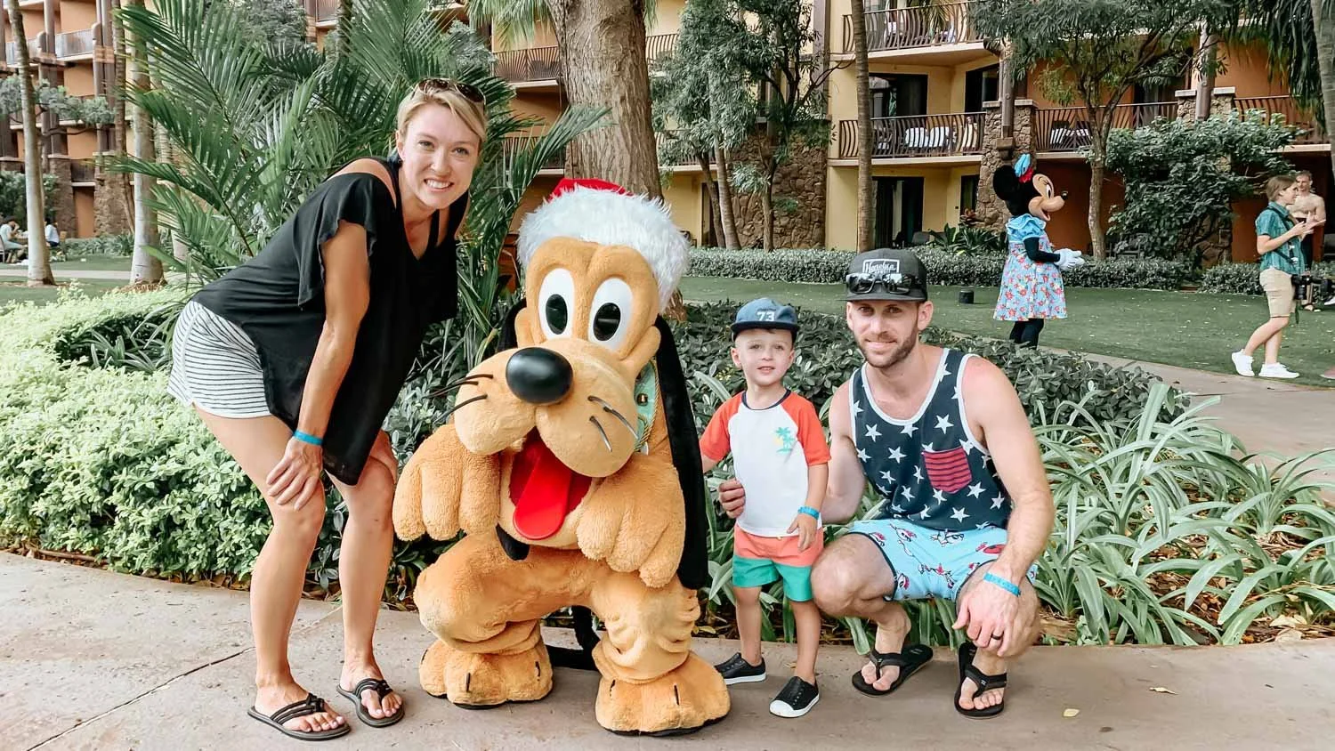 Family smiling with the Disney character Pluto at Aulani in Hawaii