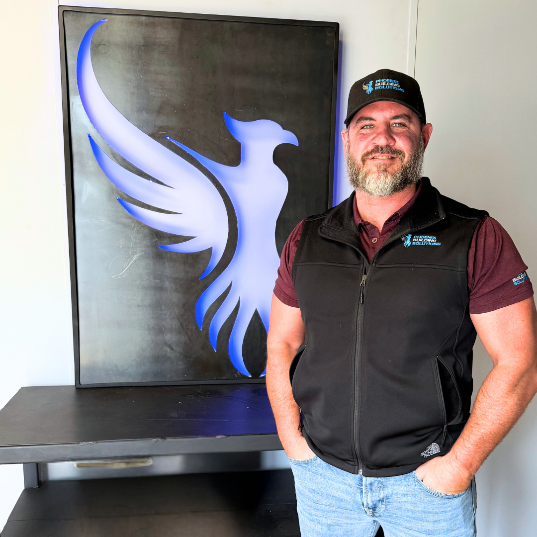 Image showcases Chris Gulledge, sales representative for Phoenix Building Solutions, standing in front of the image of a Phoenix. - Phoenix Building Solutions | Metal Supplier | Metal Buildings | Best Metal Roofs