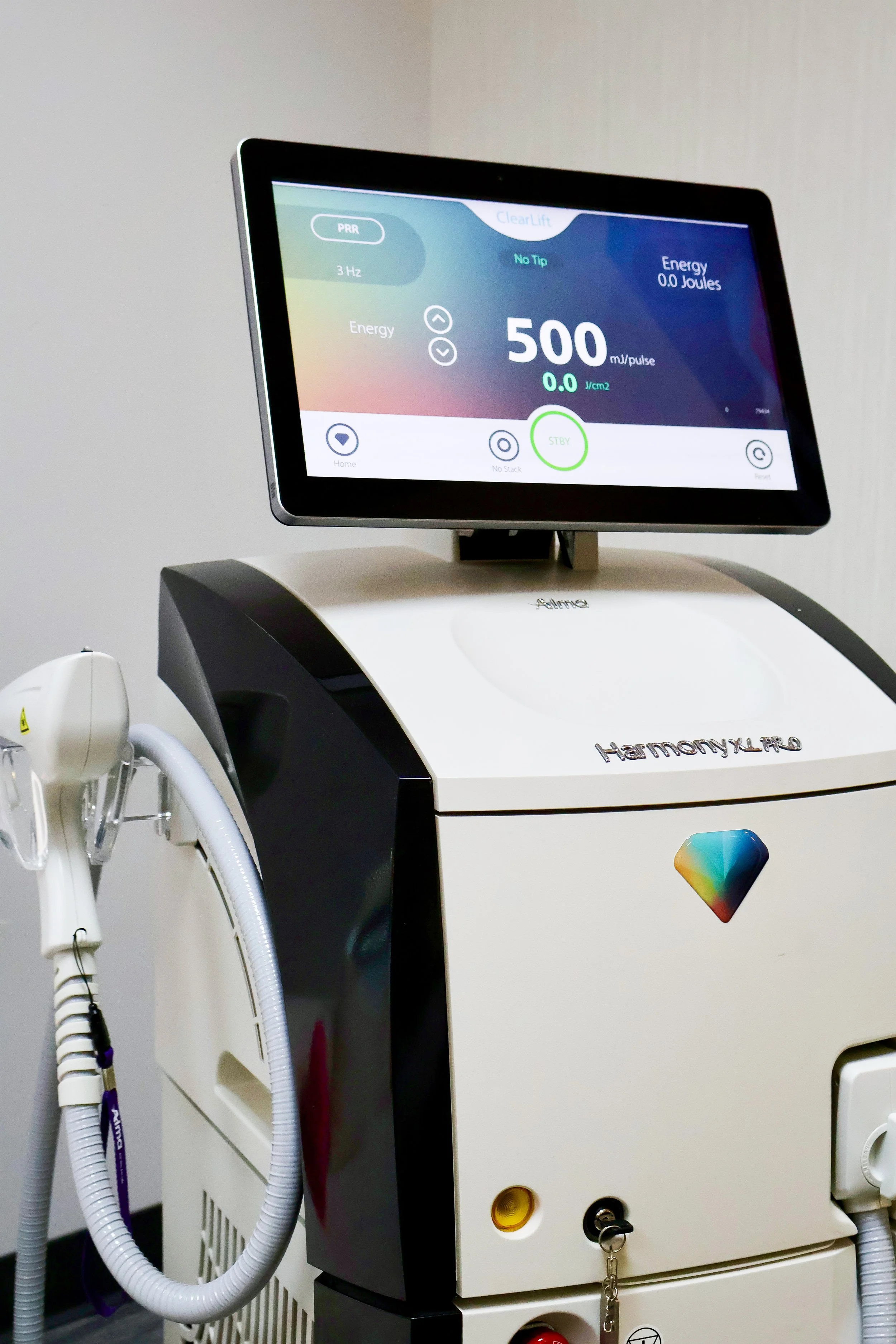 Medical laser machine with a digital display screen showing settings for energy and pulse rate.