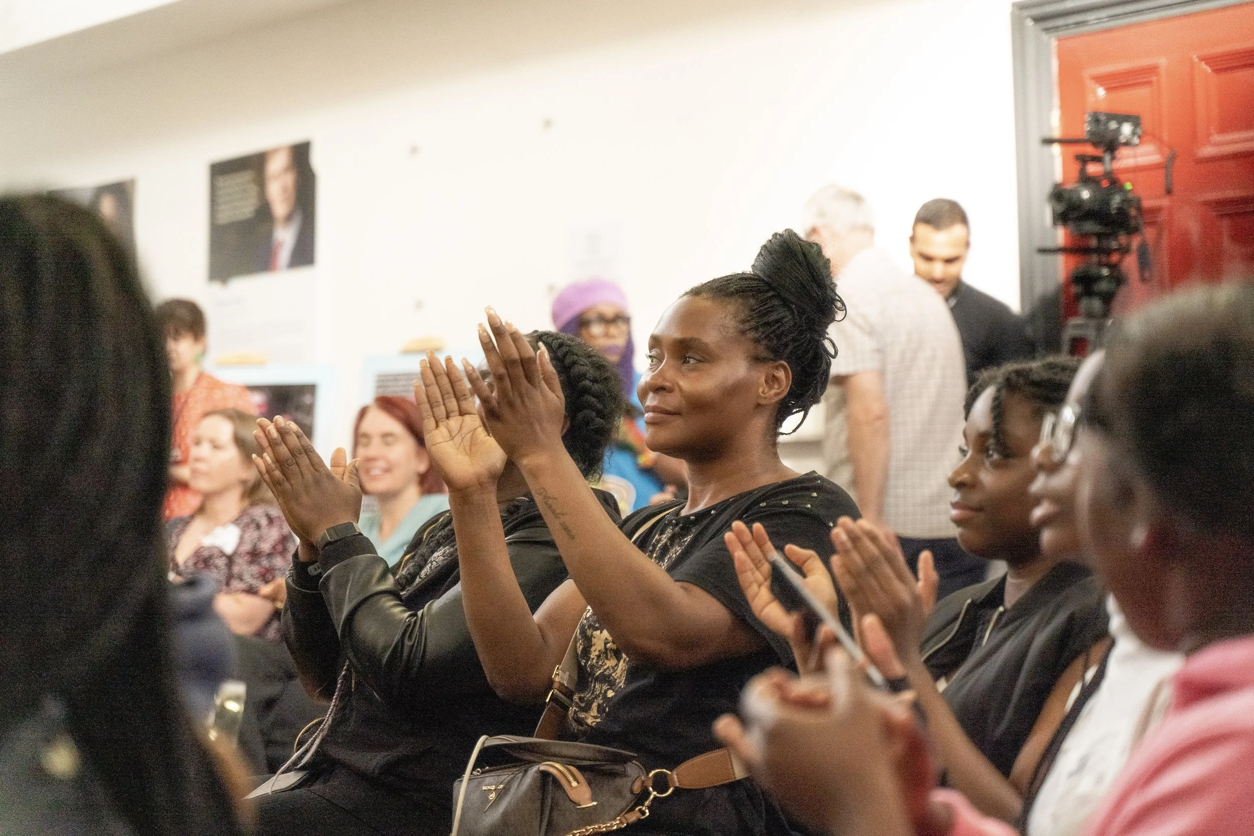 Women sat in a row clapping at a community event