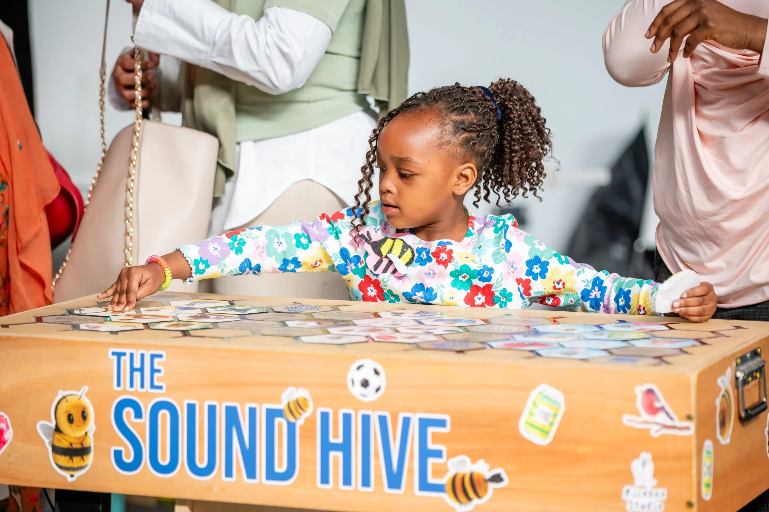 Small girl with braids playing with The Sound Hive artwork