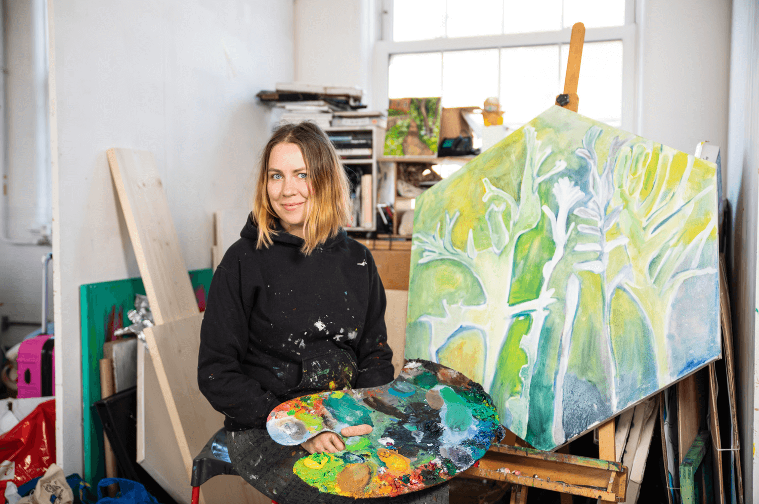 A portrait of Eastern European artist Elena Juzulenaite surrounded by her paintings