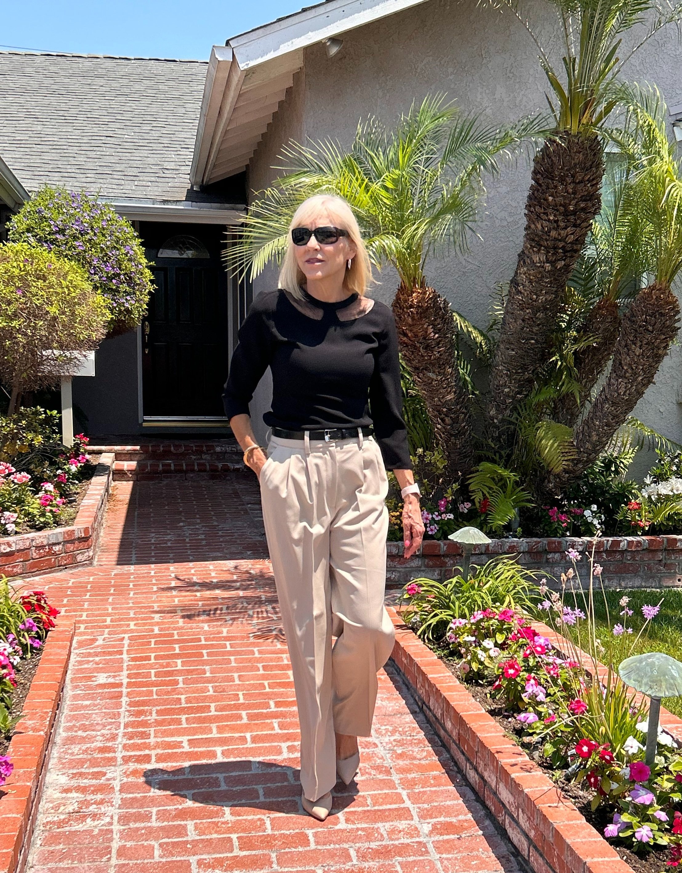 A woman going to a summer funeral in lightweight beige pants with a black blouse.