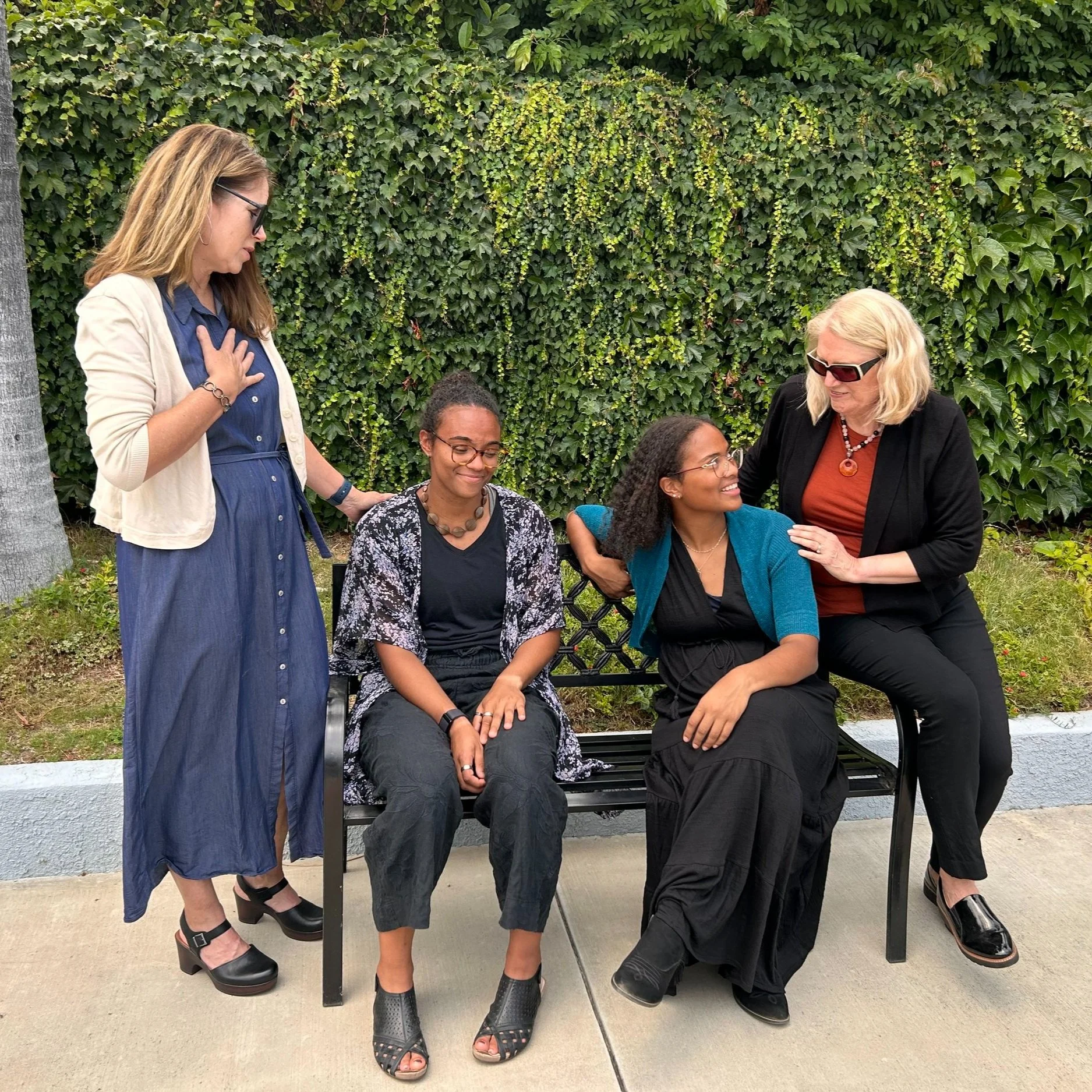 2 women grieving with 2 children while modeling women's funeral attire