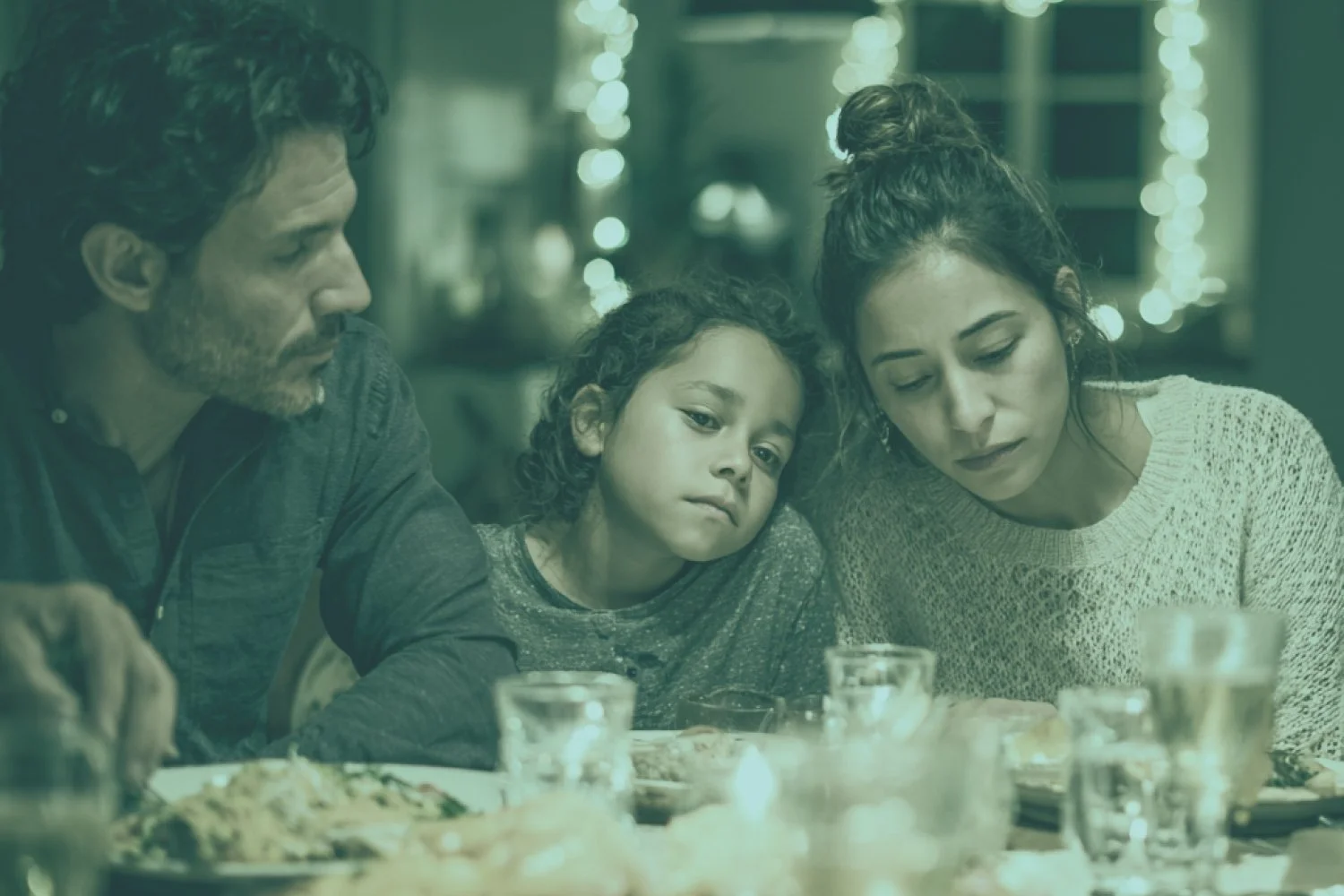 Family with child in the center looking somber while having holiday meal