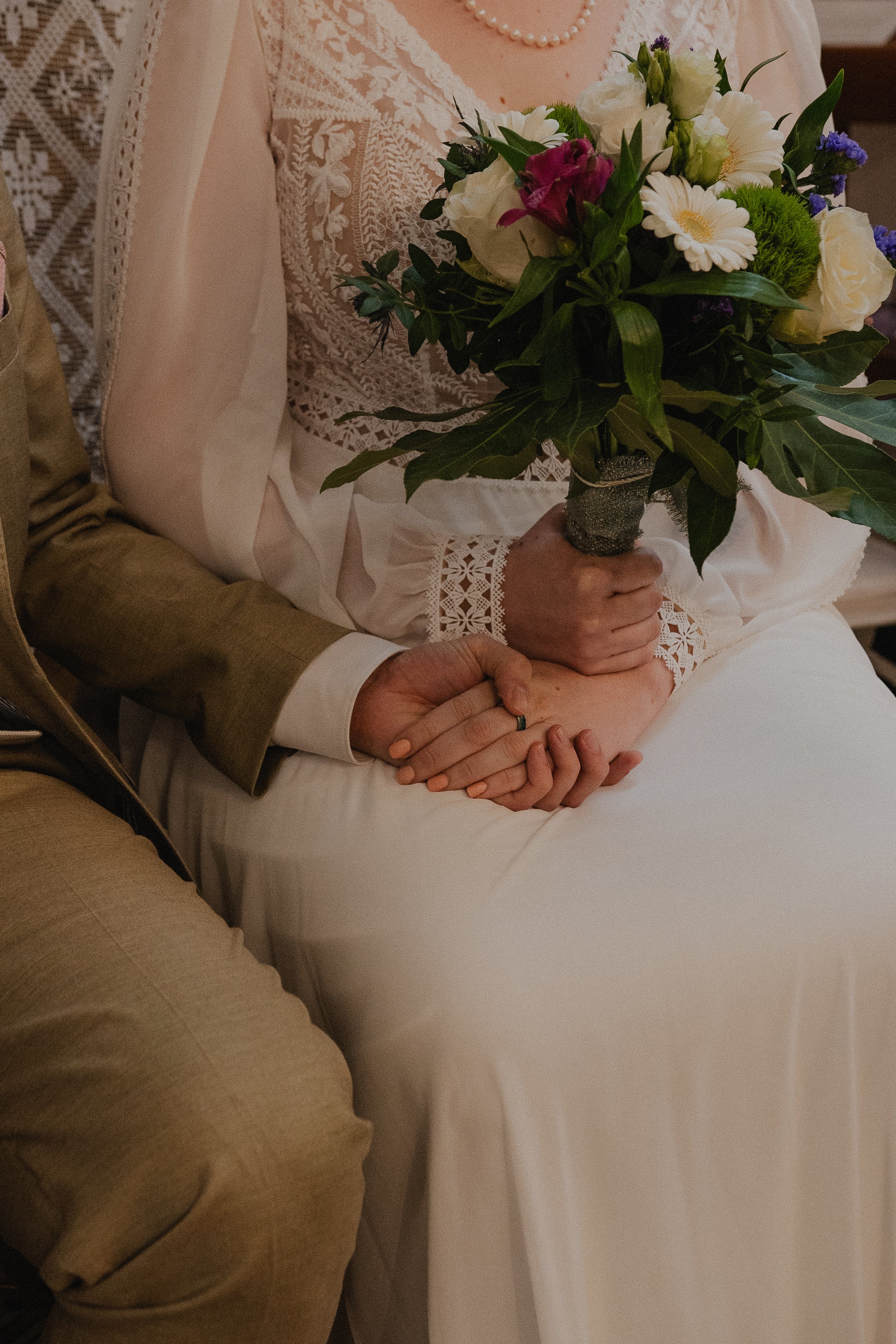 Bride holding bouquet sitting beside groom