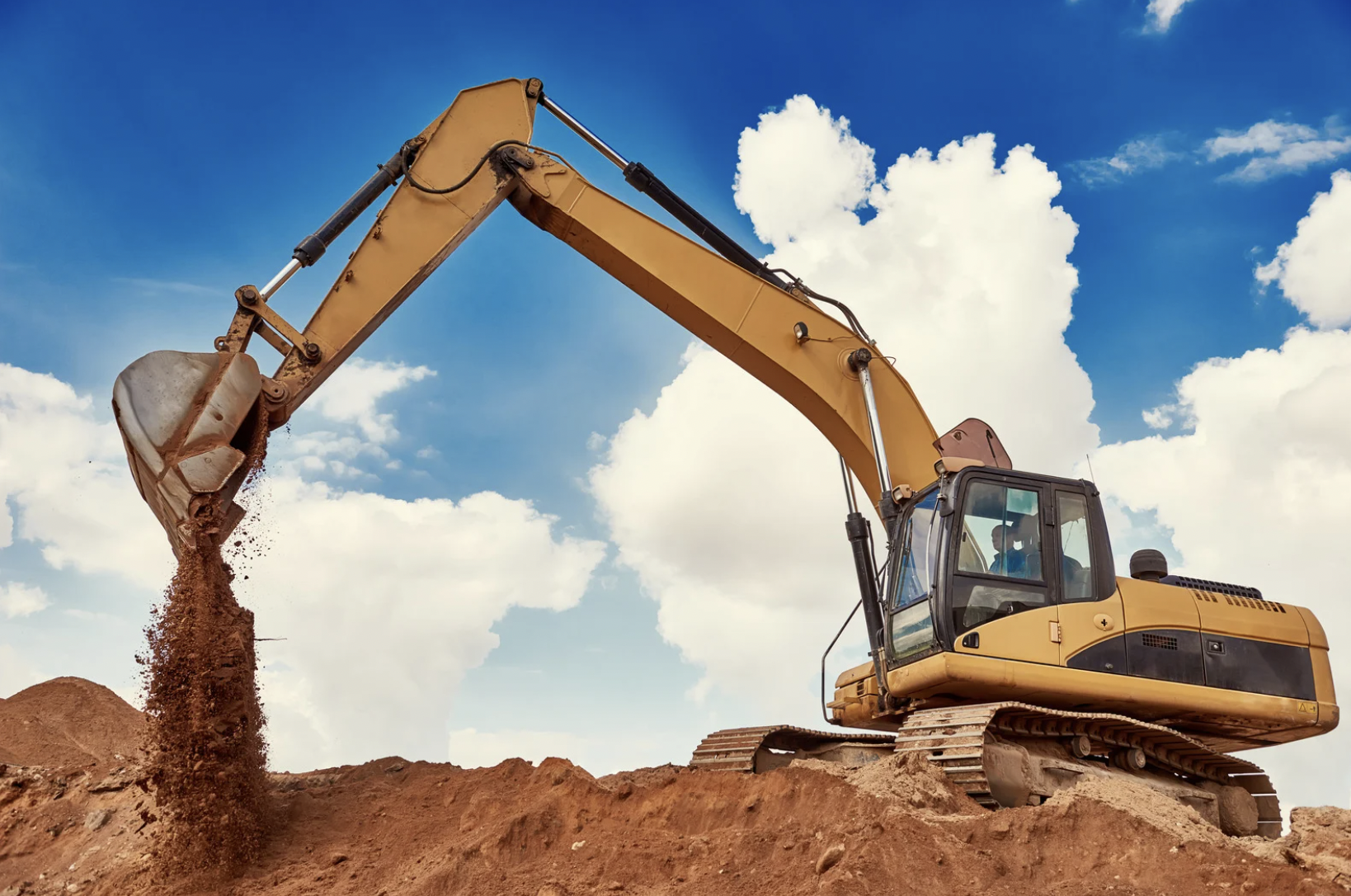 Excavator loading soil into a truck at a construction site for Sierra Excavations trucking services in Utah