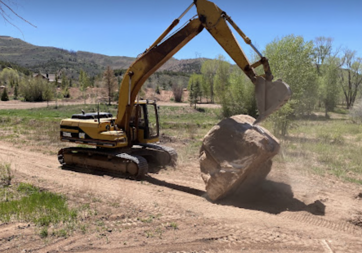 Excavator loading soil into a truck at a construction site for Sierra Excavations trucking services in Utah