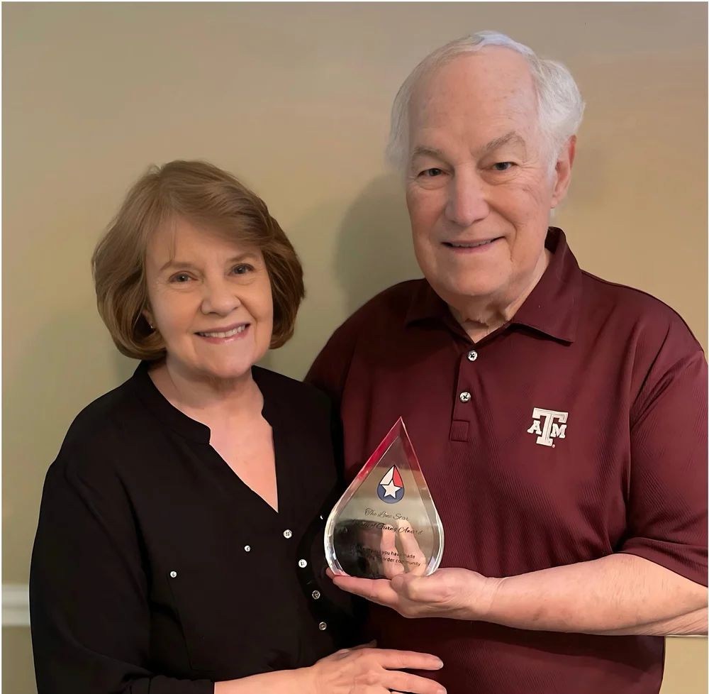 The Wagners with their Legacy of Giving award, a clear glass teardrop engraved with the Lone Star star-and-drop mark