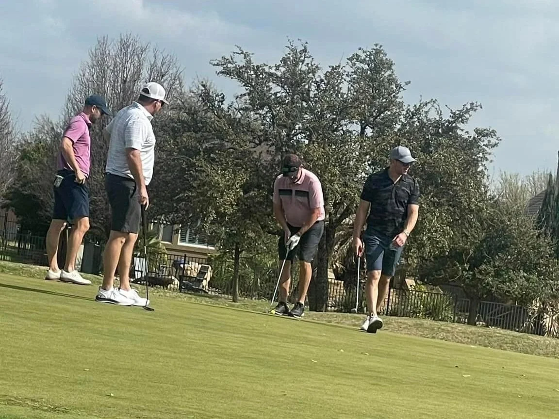Four golfers on a green at Heroes in the Hills, one lining up a putt