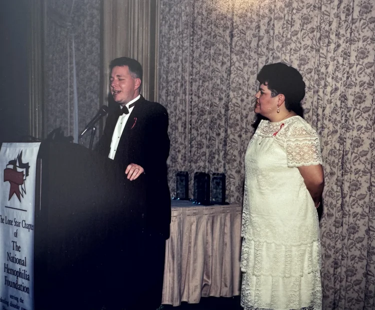 A man speaking at a lectern draped with the Lone Star Chapter banner, awards set out on the table beside him