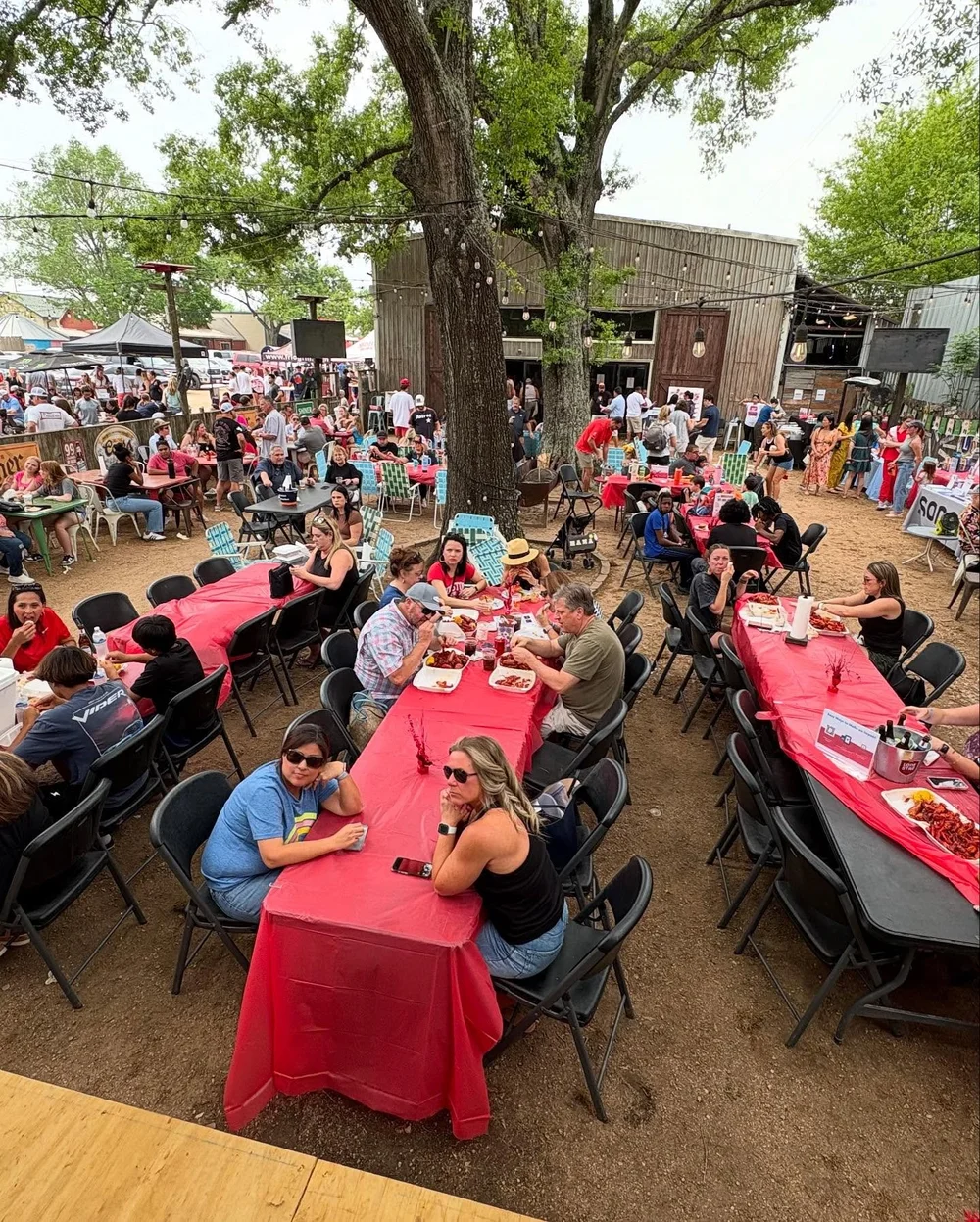 Long tables of people eating crawfish under the trees at The Barn