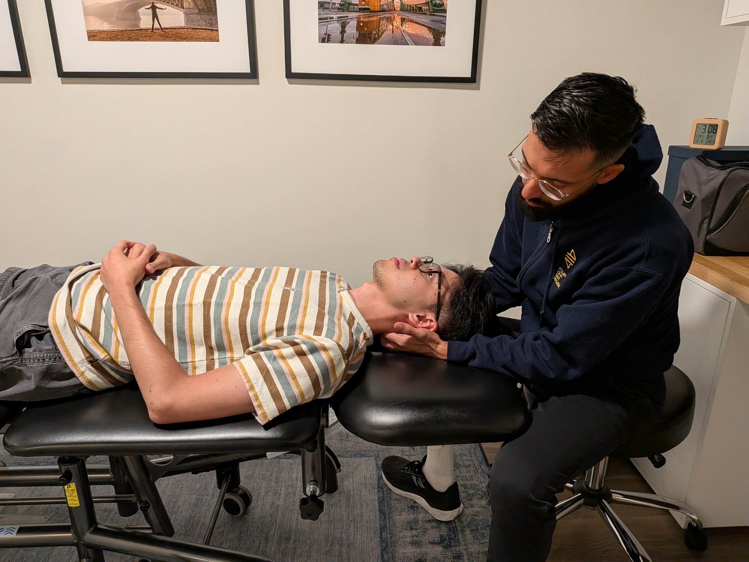 Dr. Sahib Gill assessing a patient's neck while the patient is lying on a treatment table