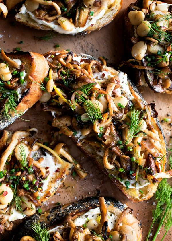 Gourmet toast topped with sautéed mushrooms, white beans, herbs, and cream cheese on rustic bread.