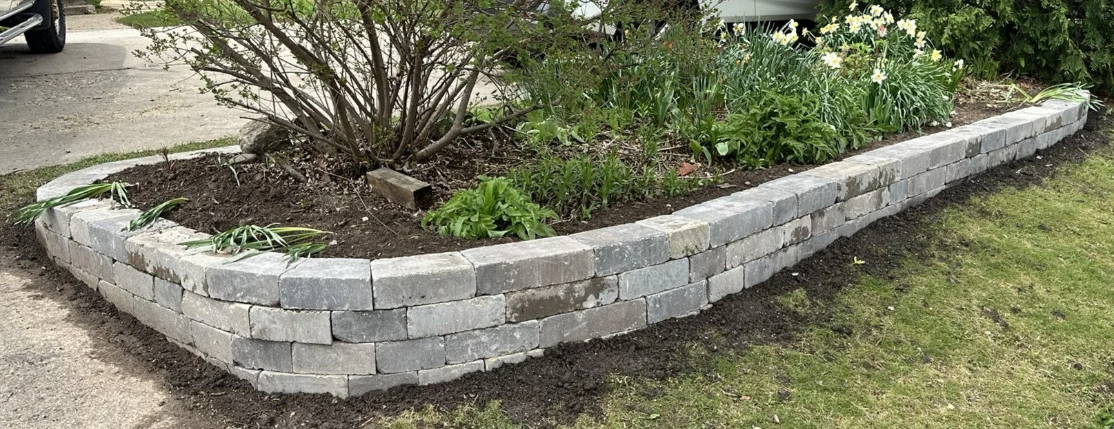 Three-course tumbled block garden wall around a corner planting bed in Middleton, WI