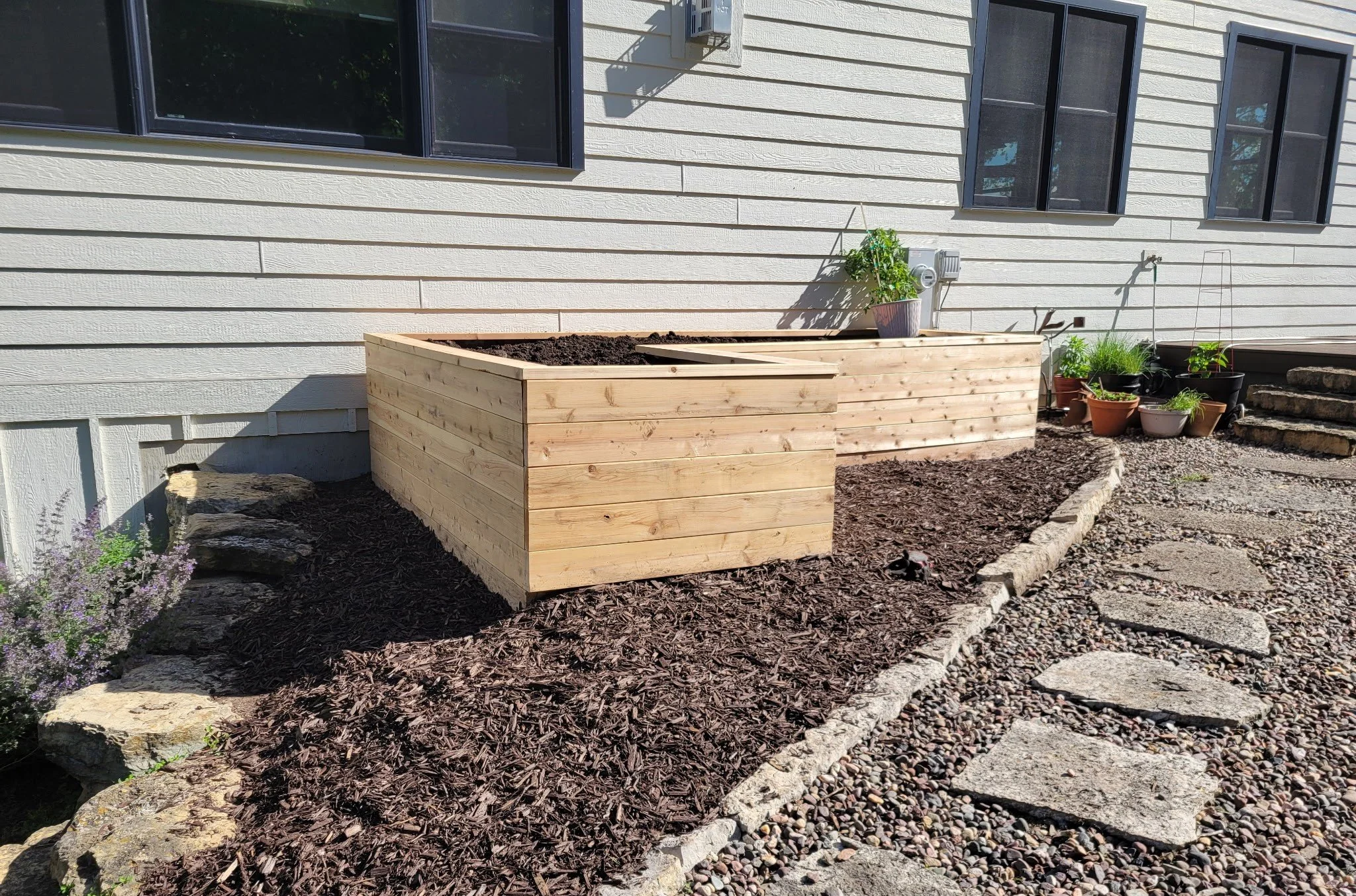 Finished raised garden bed and mulched bed beside a stone-edged gravel path in Mount Horeb, WI