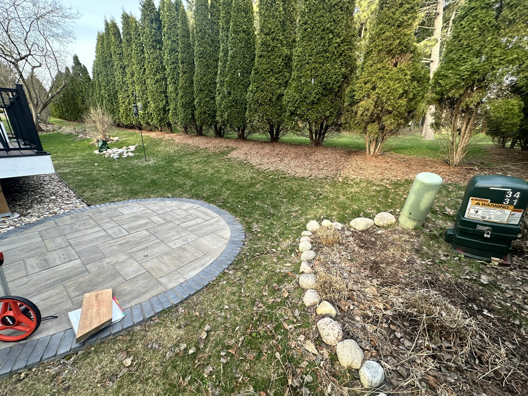 scattered fieldstone around a young tree and exposed utility boxes in a Hawks Landing, Madison backyard