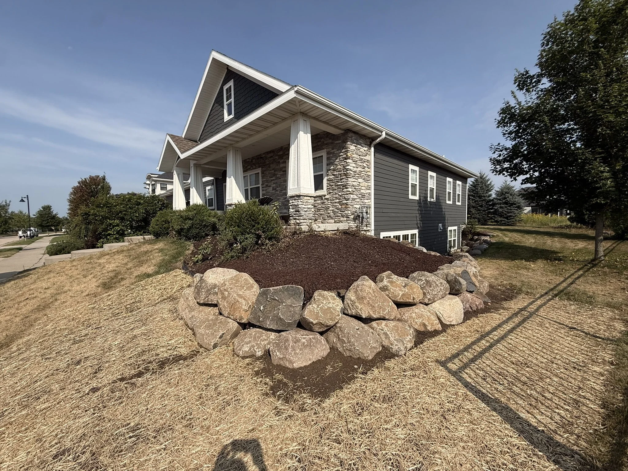 Rebuilt two-course boulder retaining wall along a foundation bed in Bishops Bay, Middleton, WI
