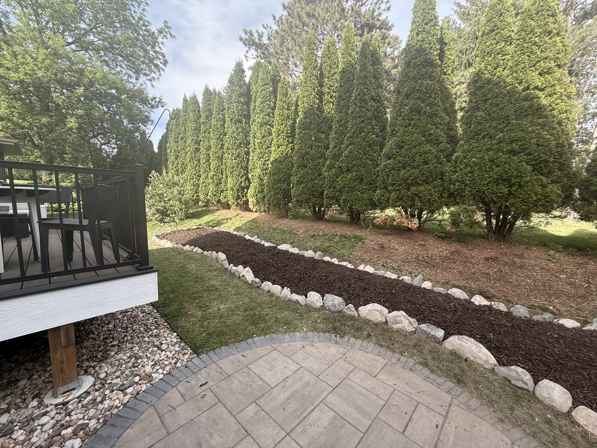 Fieldstone boulder edging around a curved mulch bed beside a paver patio in Hawks Landing, Madison, WI