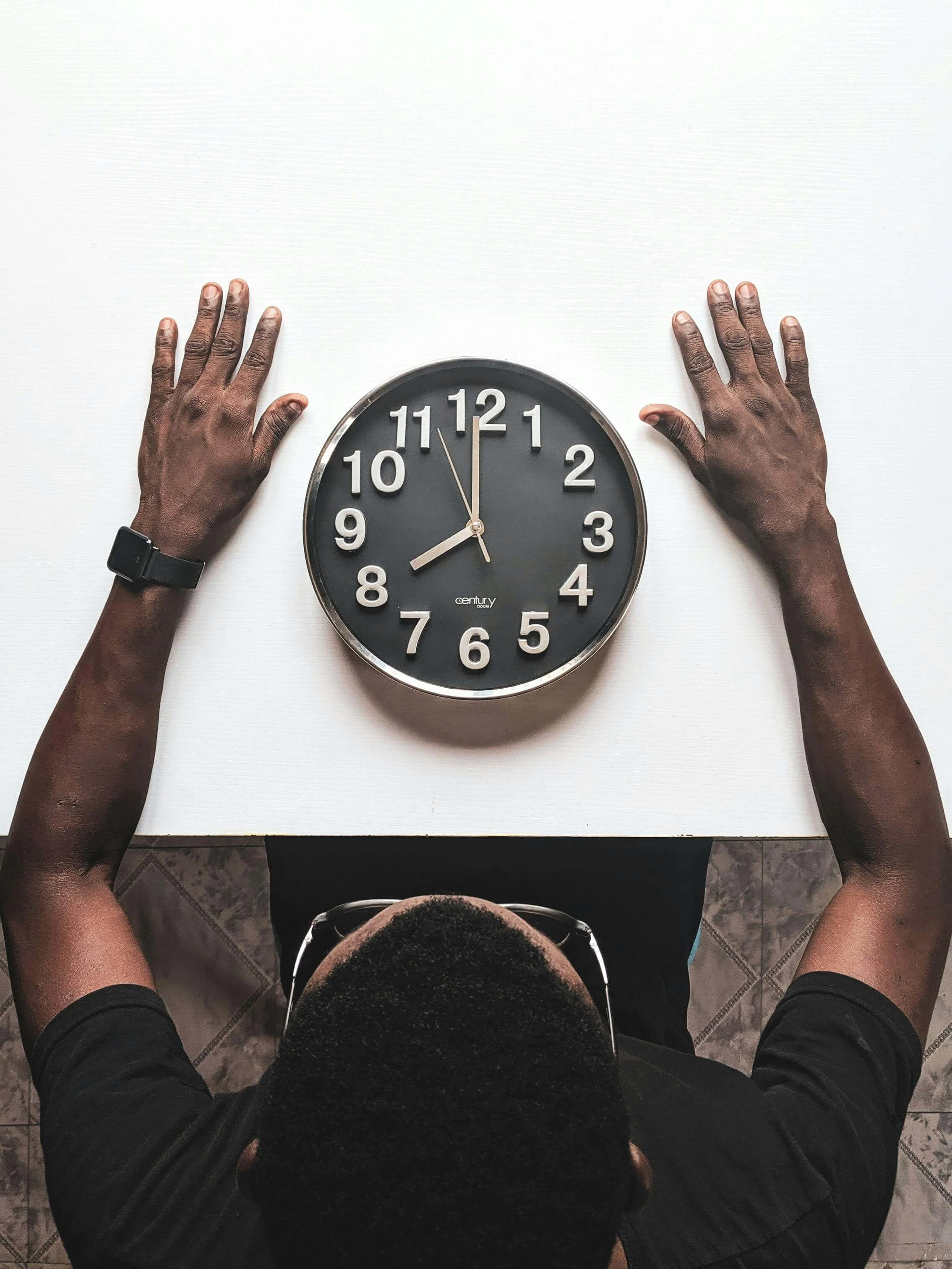 A black Man sitting in front of a large clock on the table. Burnout therapy in Bryant Park, NY can support your WFH boundaries. Learn how to beat burnout here!