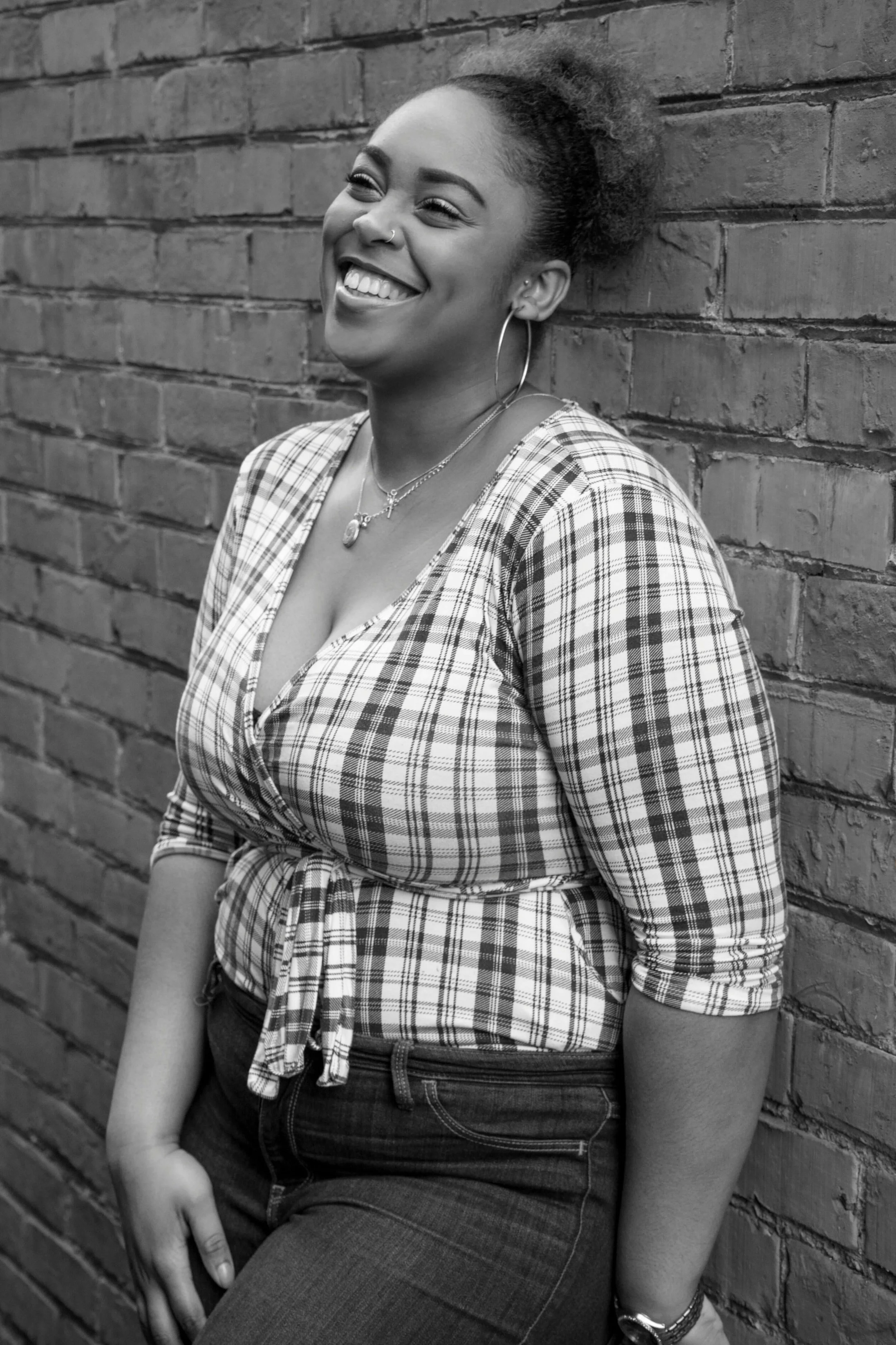 A black & white photo of a woman smiling and leaning against a brick wall. Did you know journaling can help with burnout recovery? Learn more tips in therapy for burnout in Manhattan, NY.