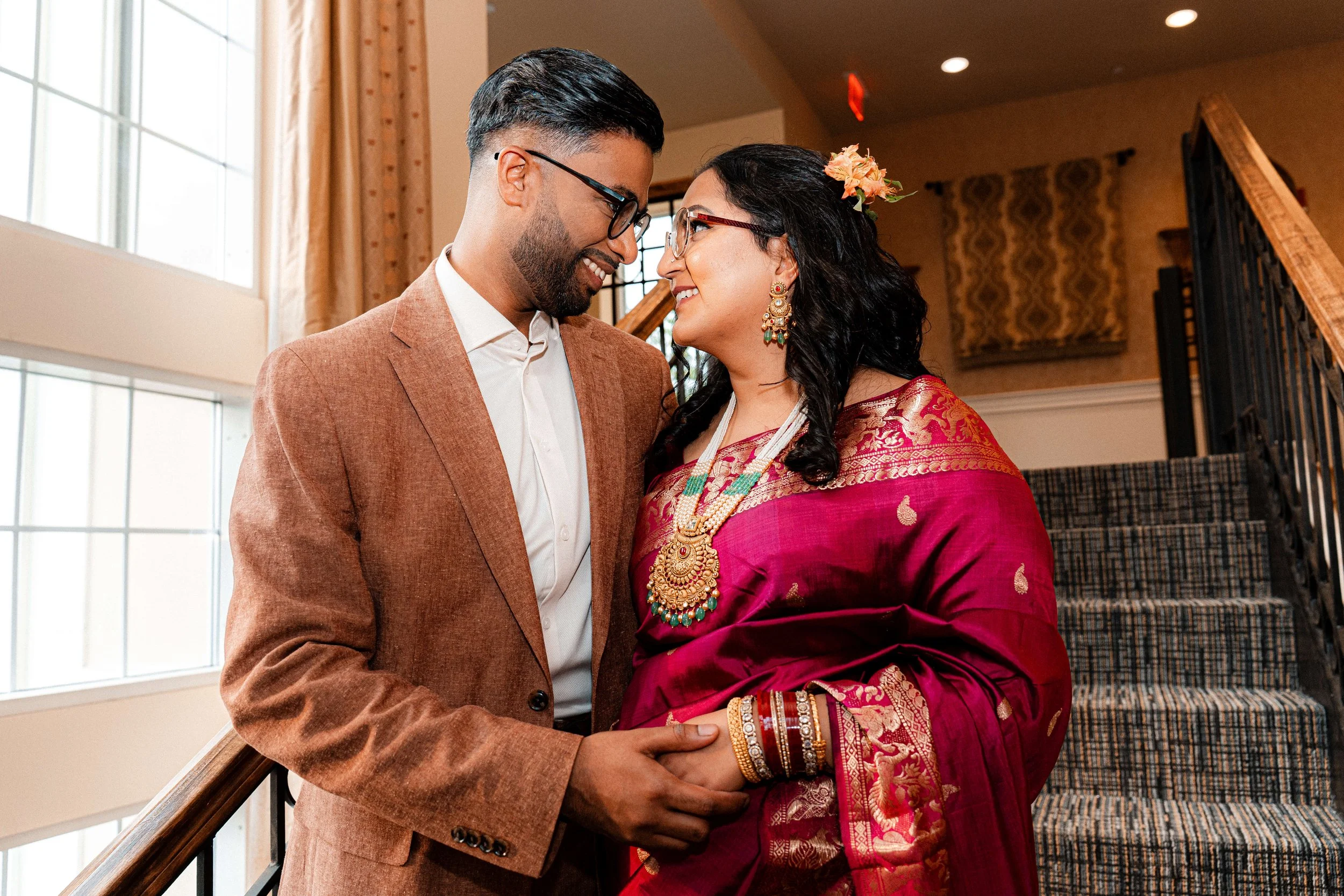 Indian couple holding hands and sharing a romantic moment during an indoor engagement photography session.