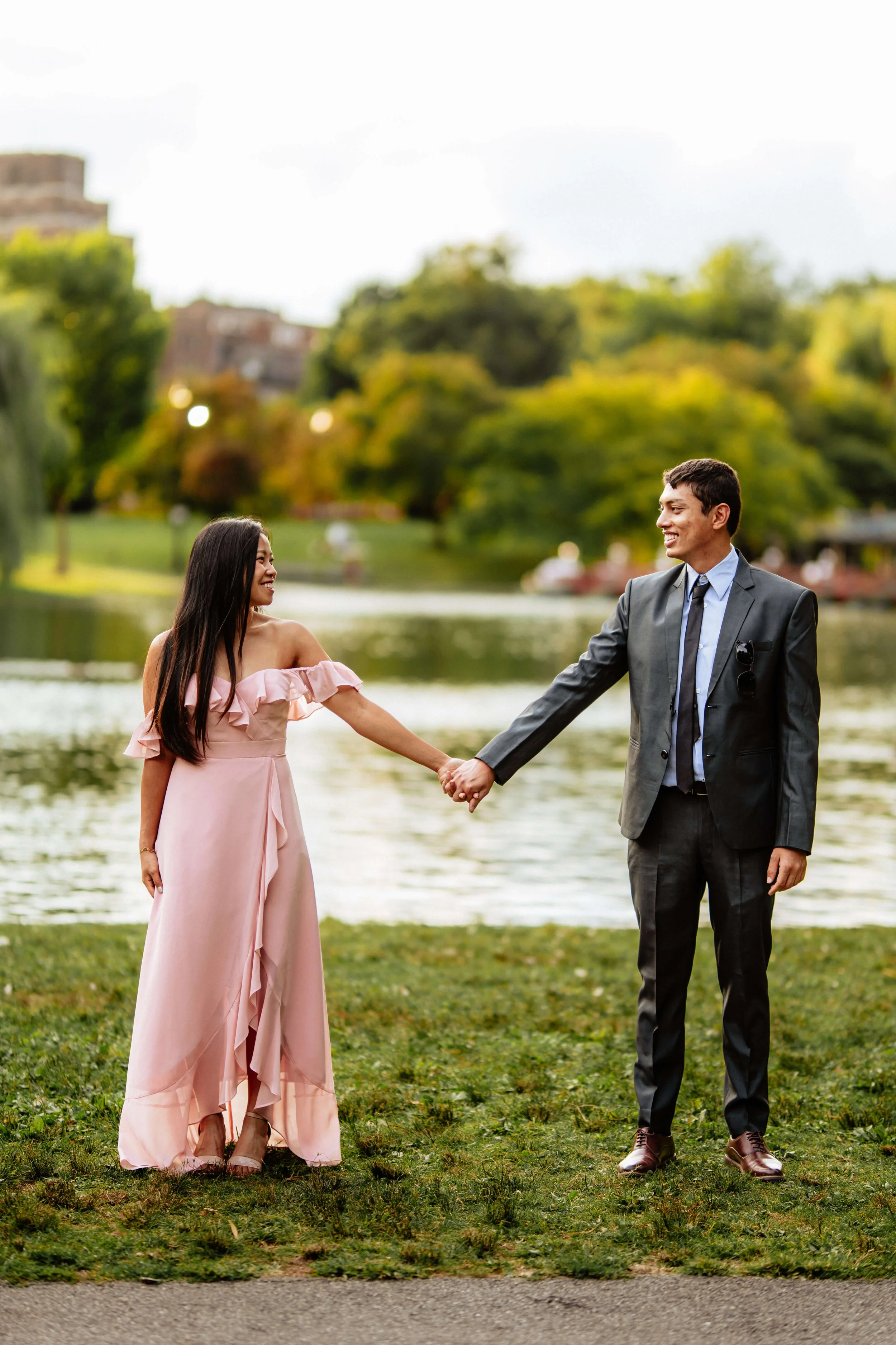 Couple holding hands and smiling during a summer couples photography session in Boston Public Garden.