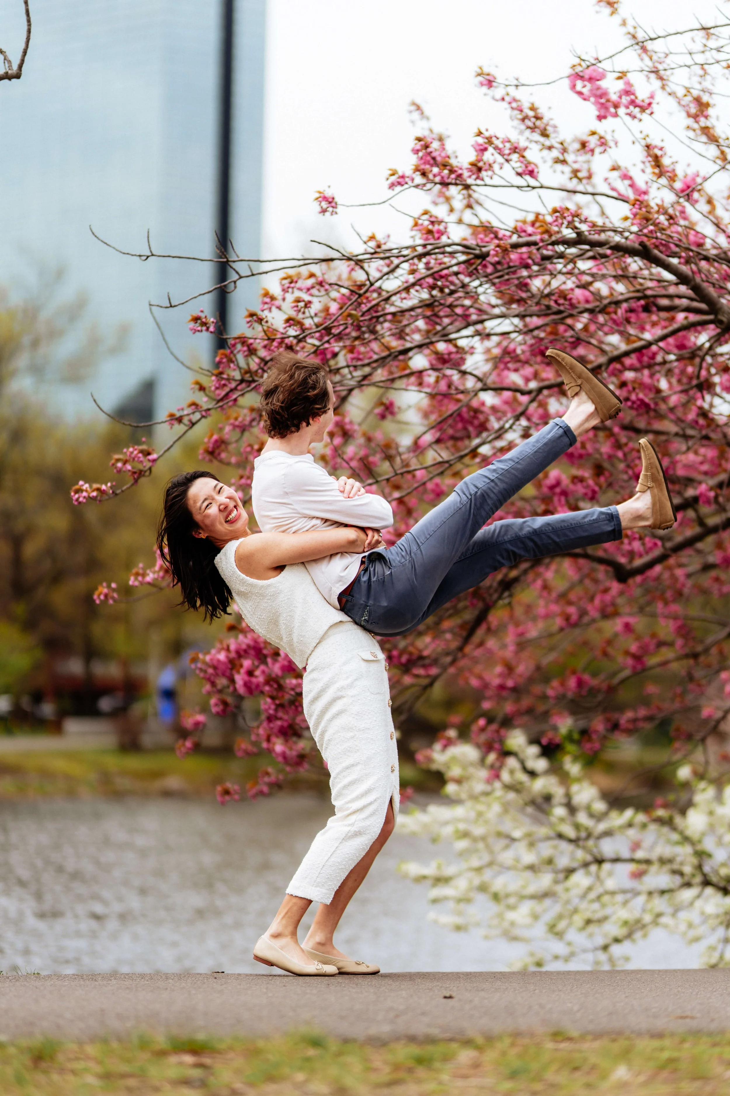 Couple embracing under cherry blossoms during a spring couples session at Charles River Esplanade in Boston.