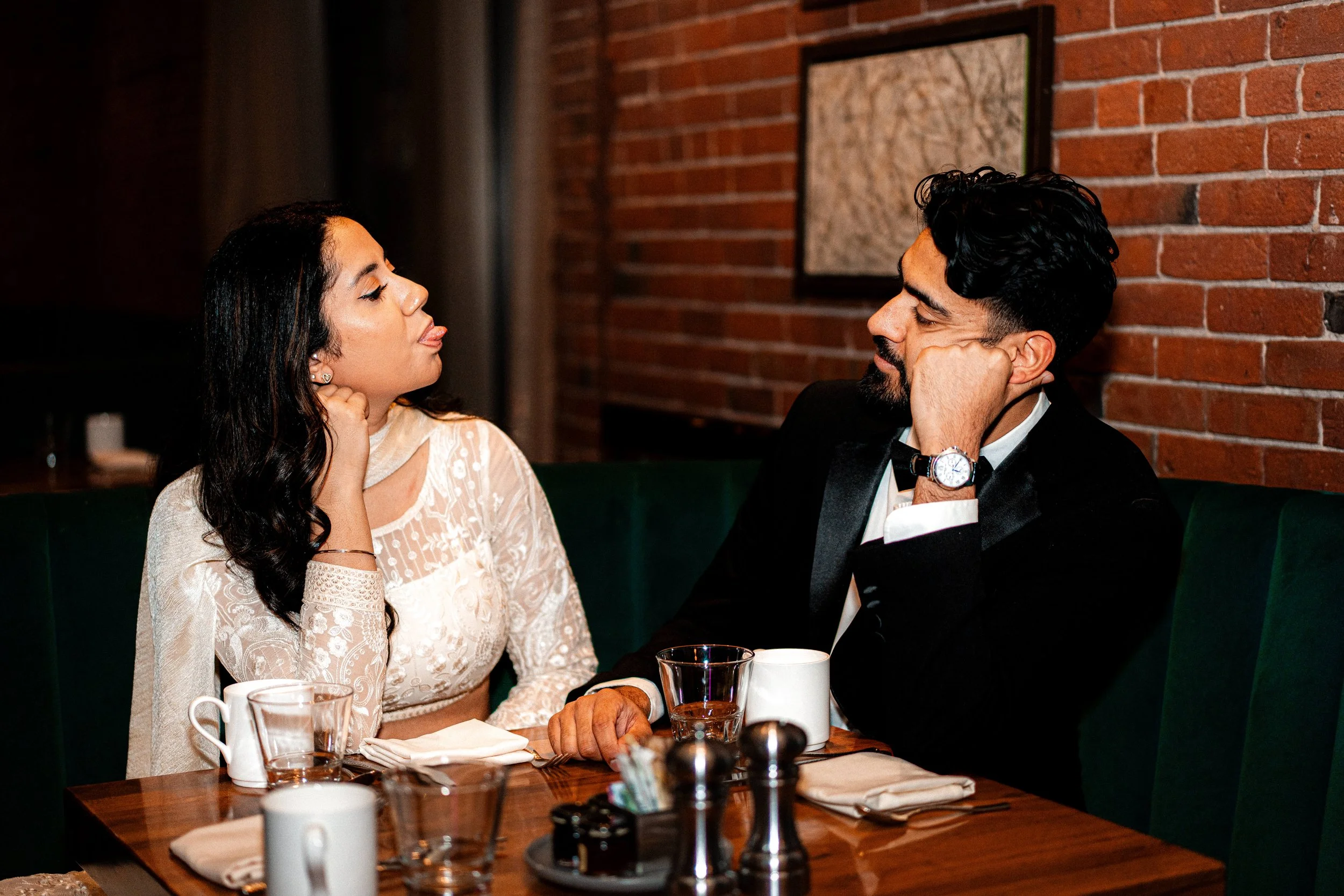 Indian couple holding hands and sharing a romantic moment during an indoor engagement photography session.