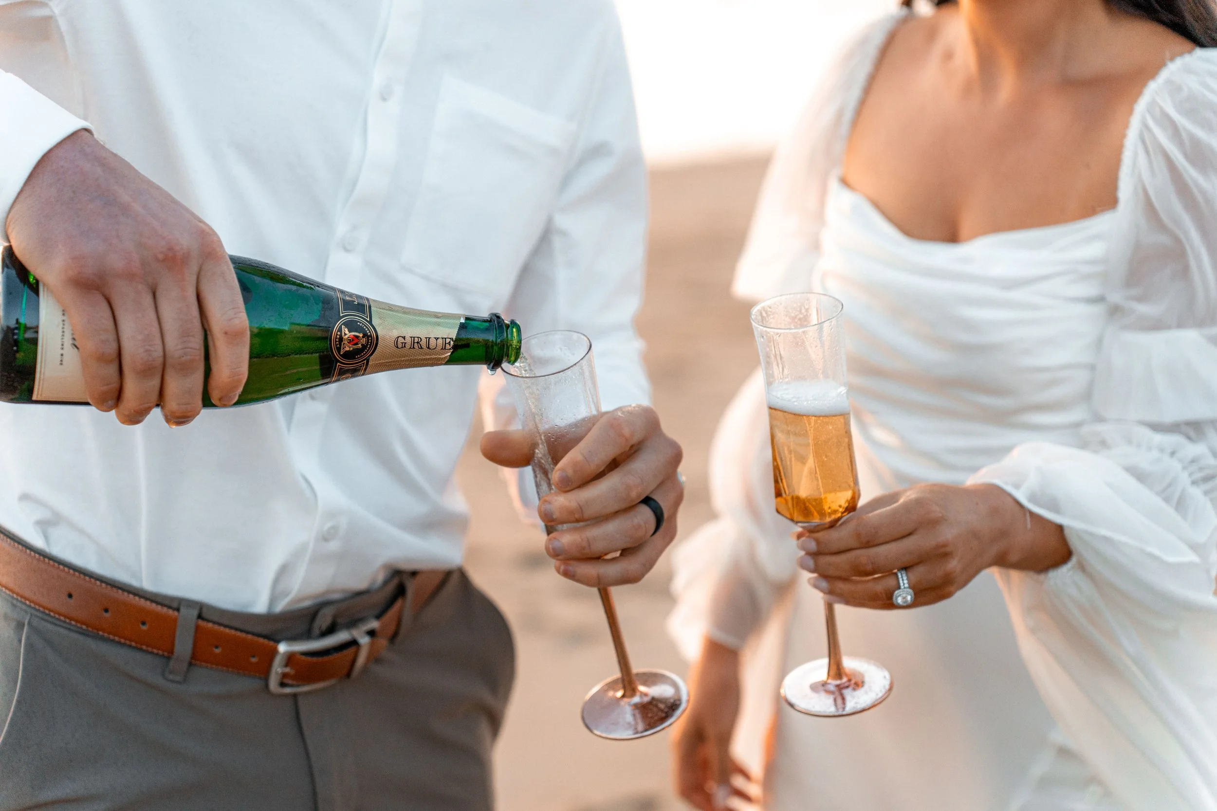 Champagne and engagement ring detail during romantic Boston beach proposal