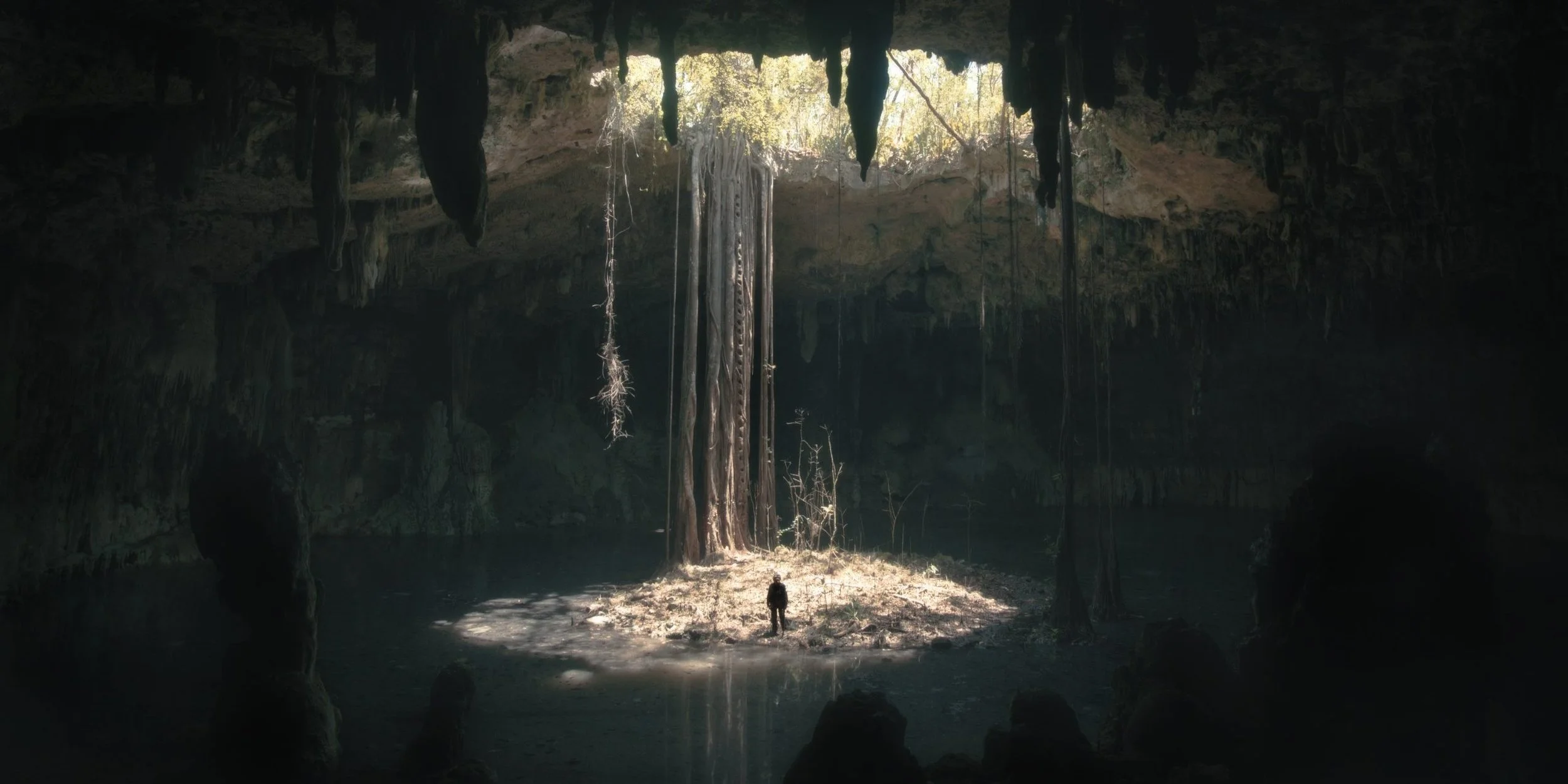 A film still from Underland showing a figure standing in a huge cave in a shaft of light