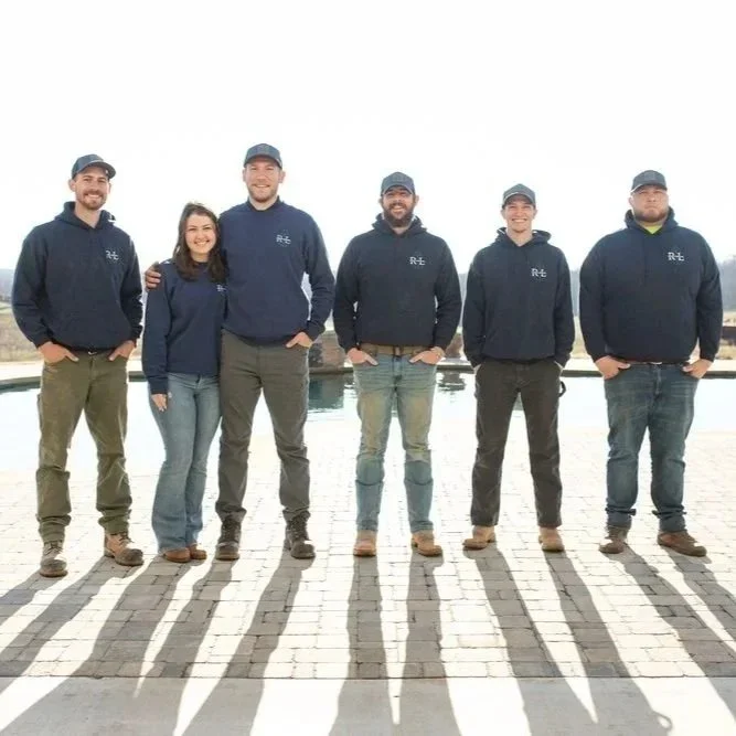 Professional contractors installing a structural stone retaining wall in a Gainesville residential backyard to prevent soil erosion and drainage issues.
