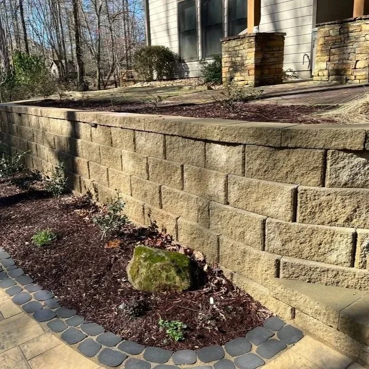 Lush Gainesville garden featuring a stone retaining wall, Spanish moss-draped live oaks, blooming azaleas, and flowing, informal woodland plant beds.