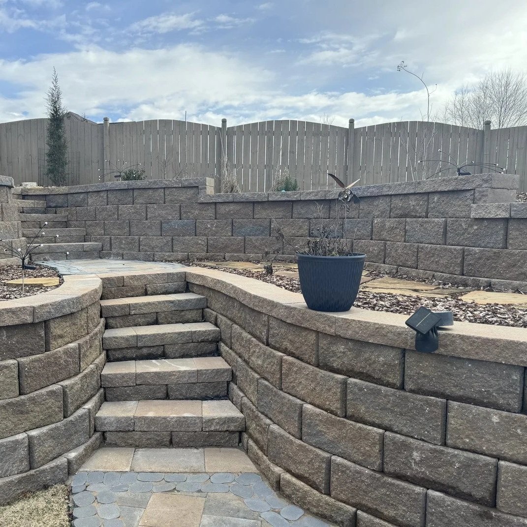 Retaining wall in Gainesville showing the concrete footing, gravel backfill, drainage pipe, and soil.