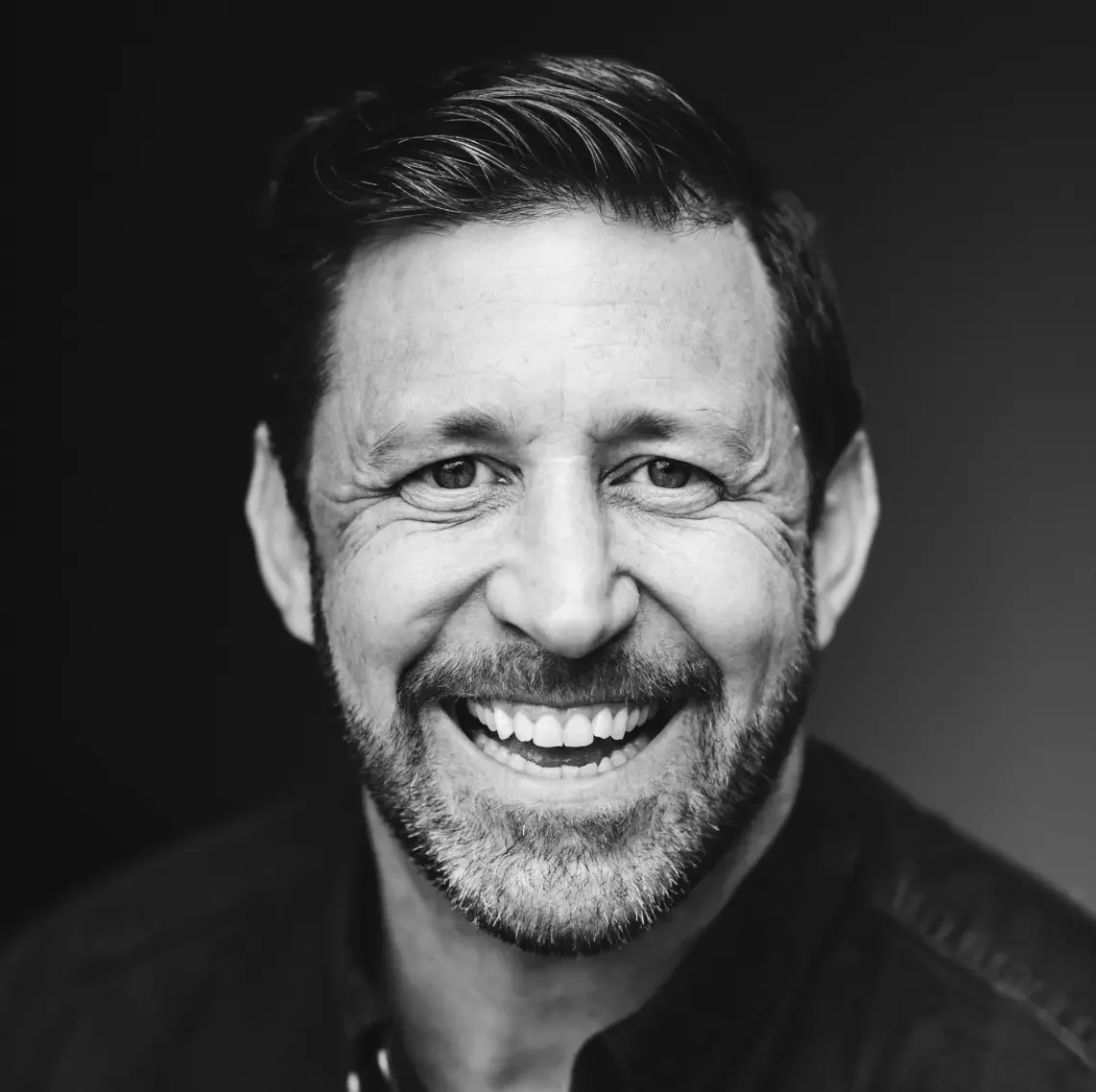 Black and White IMage of Jim Moss - mid 40's, big smile, bit of a beard, cleanly styled dark hair and lite skin.