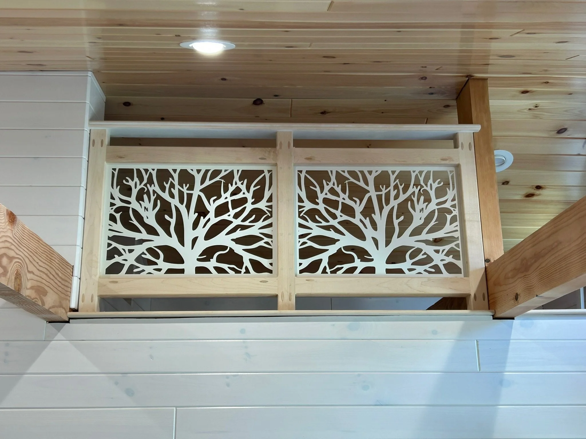 Wooden barrier with a decorative tree branch pattern.