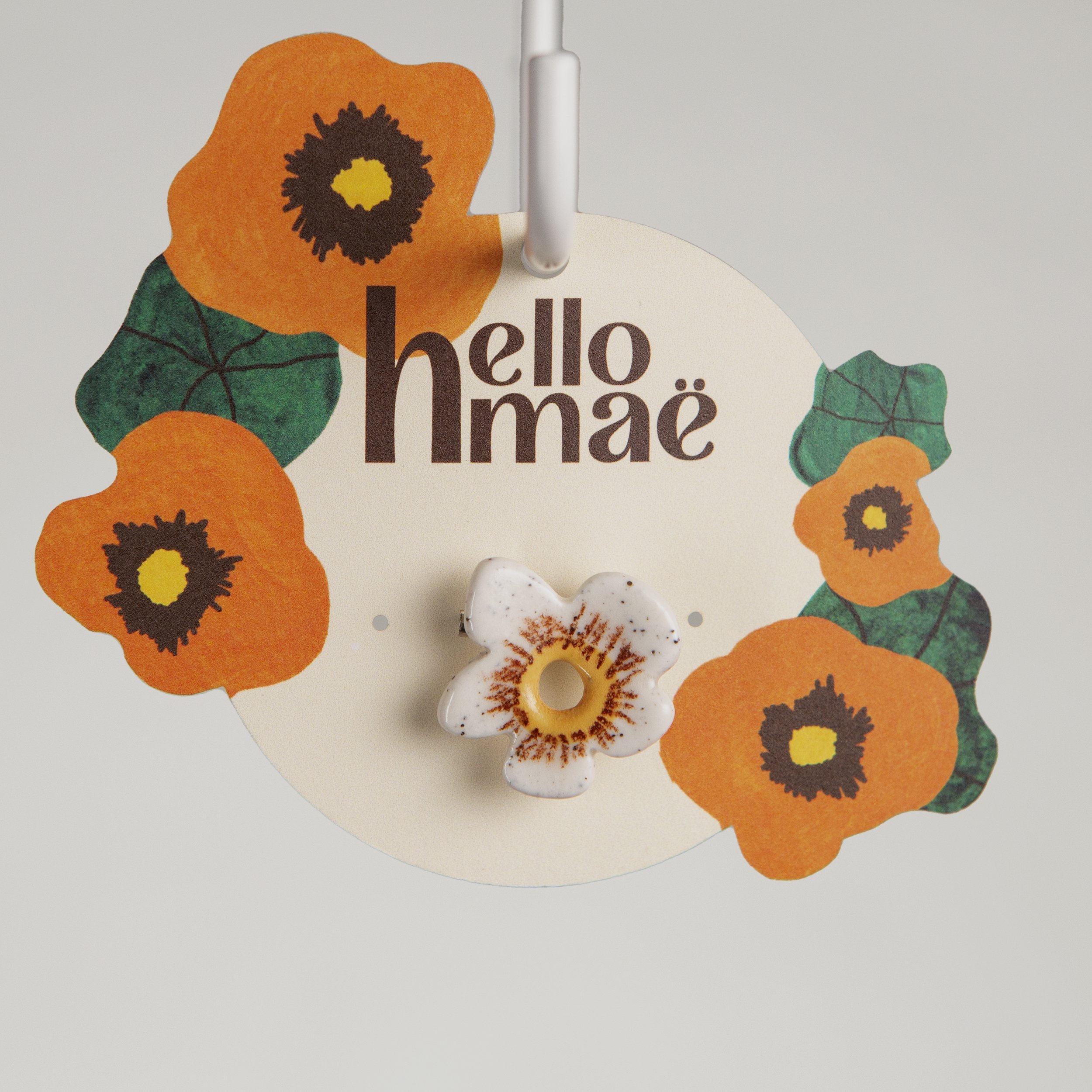 Handmade ceramic brooch with a glossy white flower, photographed on a neutral background