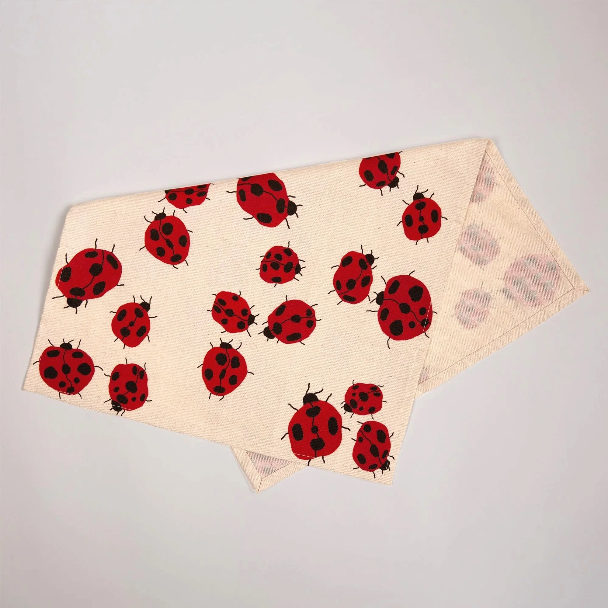 Colourful Loveliness tea towel featuring a playful print of red ladybugs and garden-inspired details.
