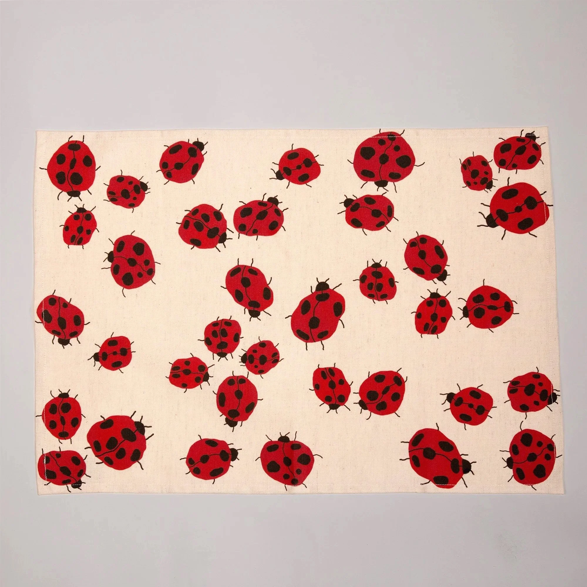 Colourful Loveliness tea towel featuring a playful print of red ladybugs and garden-inspired details.
