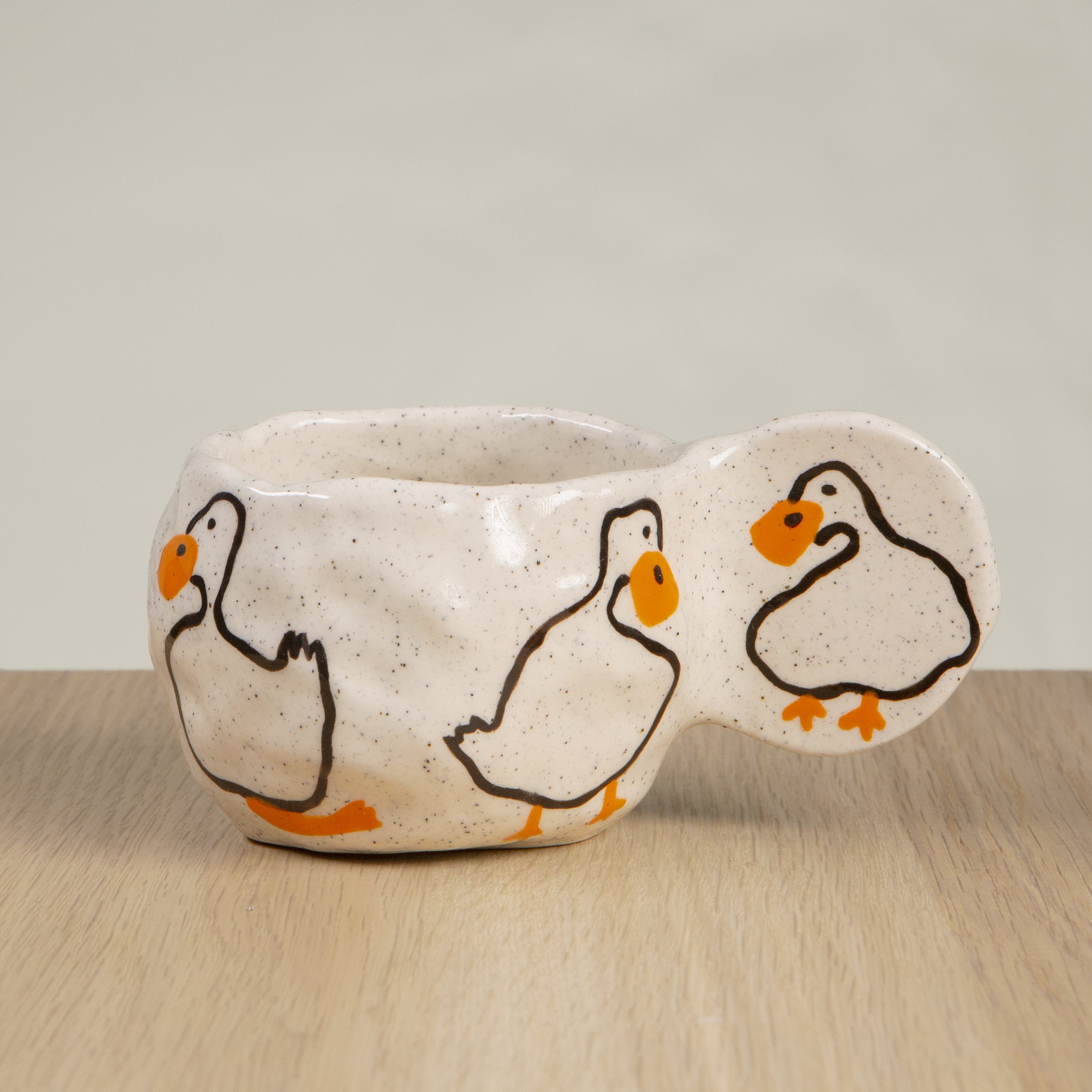 Handmade ceramic coffee cup with hand-painted loving ducks, crafted from speckled clay in Melbourne with a cute petal handle. Holds approximately 150ml.