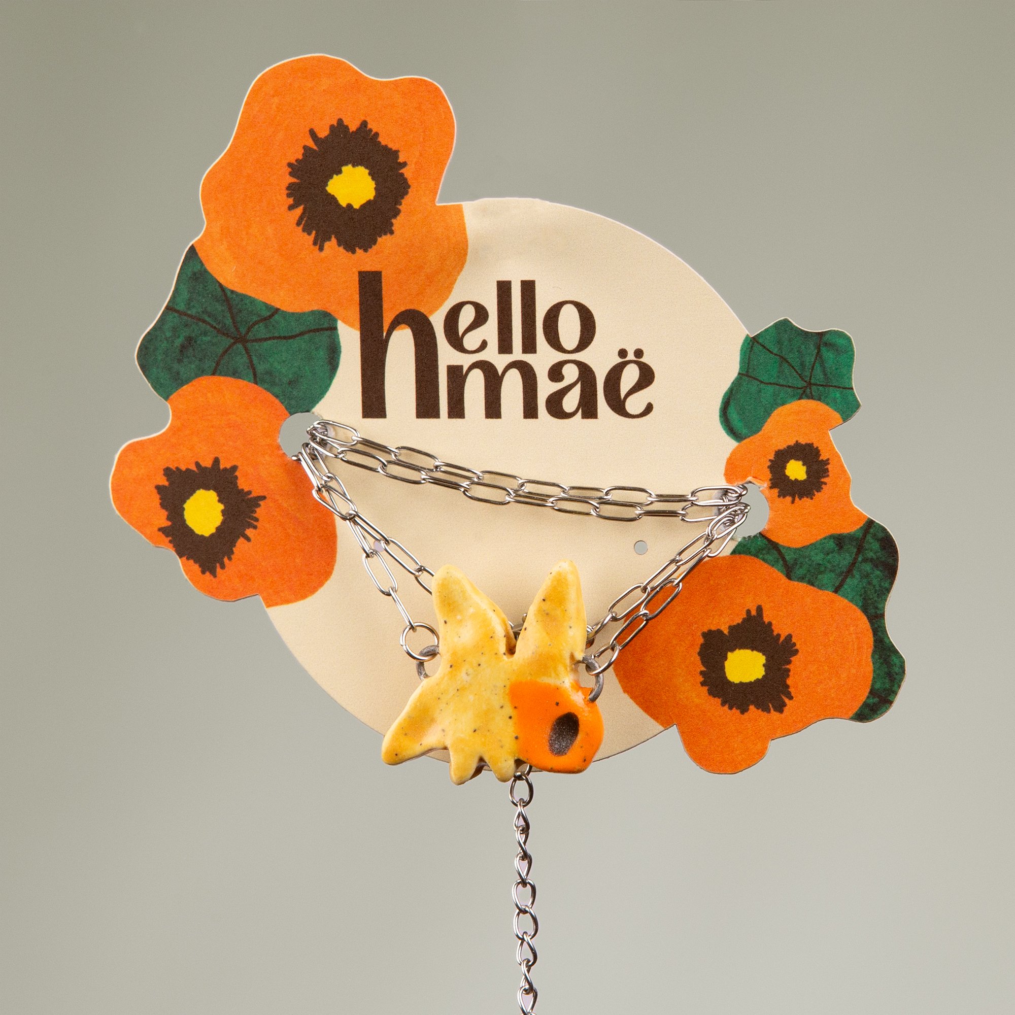 Handmade ceramic daffodil necklace featuring a playful hand-painted daffodil pendant on a silver-coloured chain.