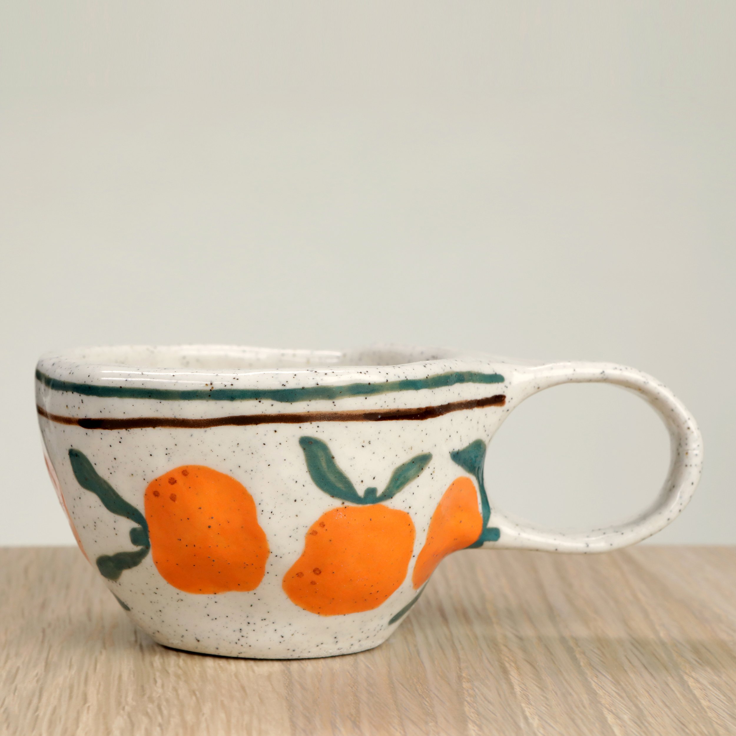 Handmade ceramic coffee cup with hand-painted mandarins & 2 lines border, crafted from speckled clay in Melbourne. Holds approximately 150ml.