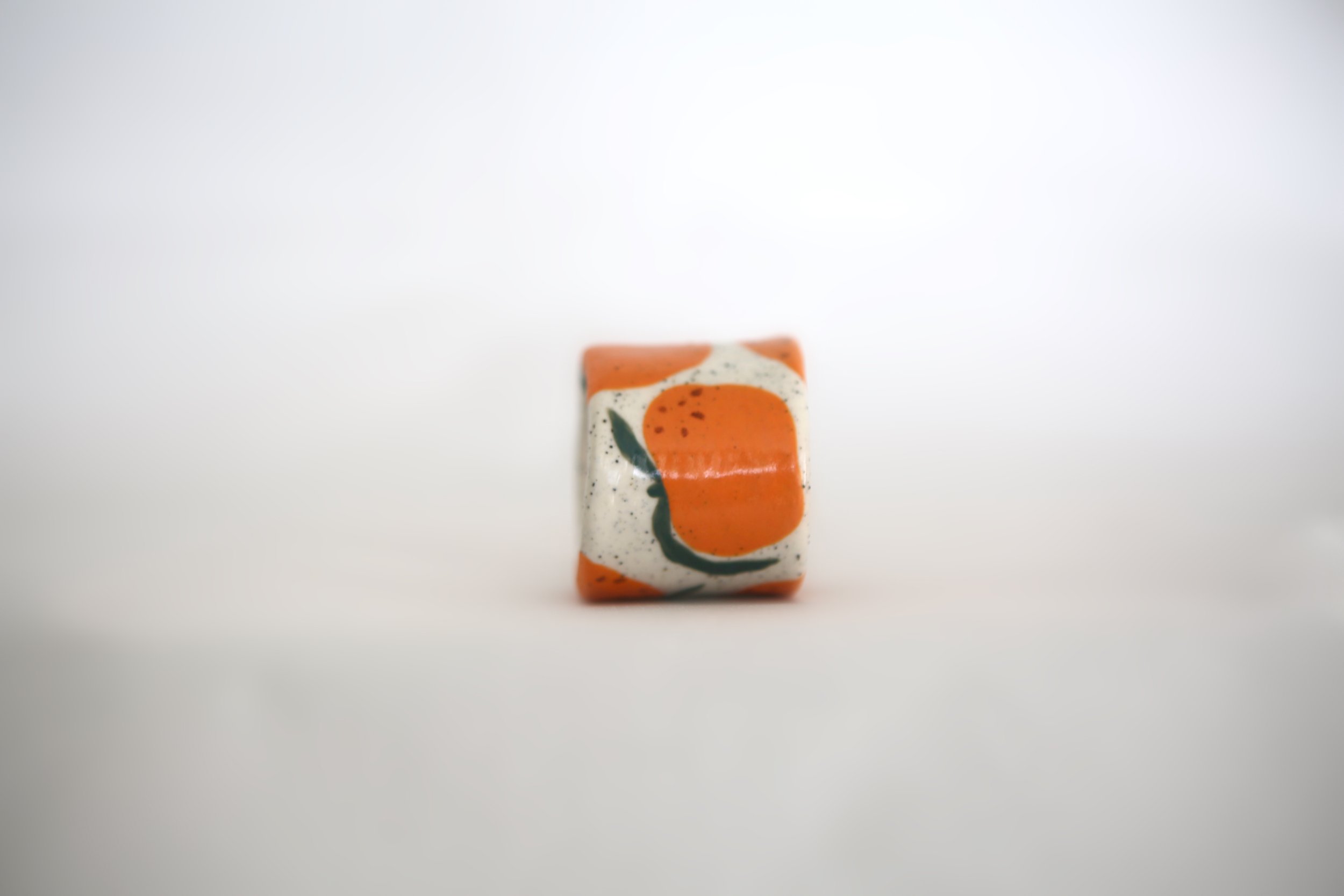Ceramic napkin ring with wonky mandarin design, off white speckled clay base, with matching napkin.