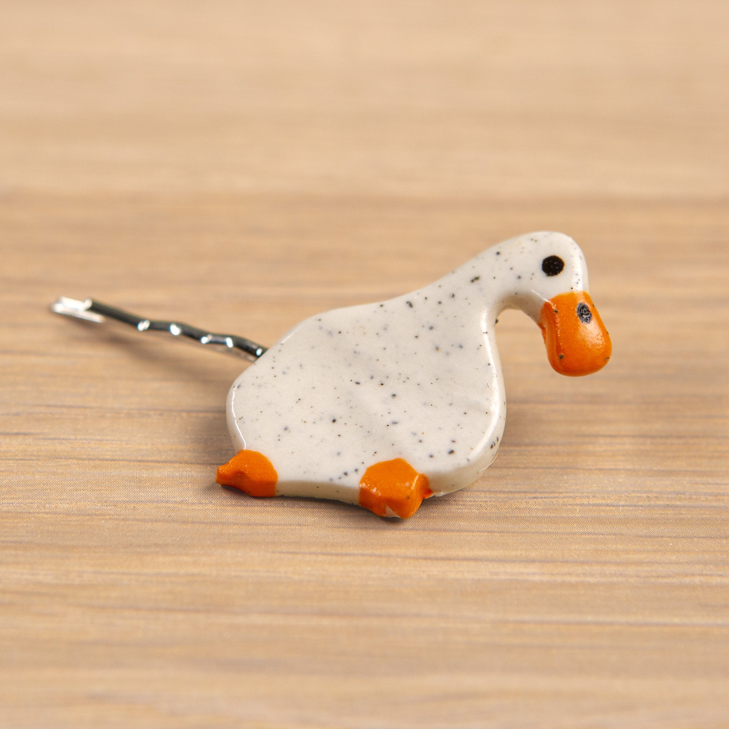 Handmade ceramic hair pin with a glossy dreamer white duck, photographed on a neutral background.