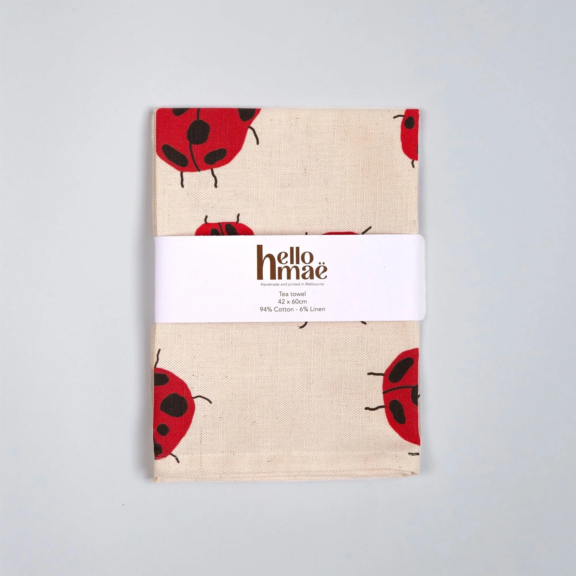 Colourful Loveliness tea towel featuring a playful print of red ladybugs and garden-inspired details.
