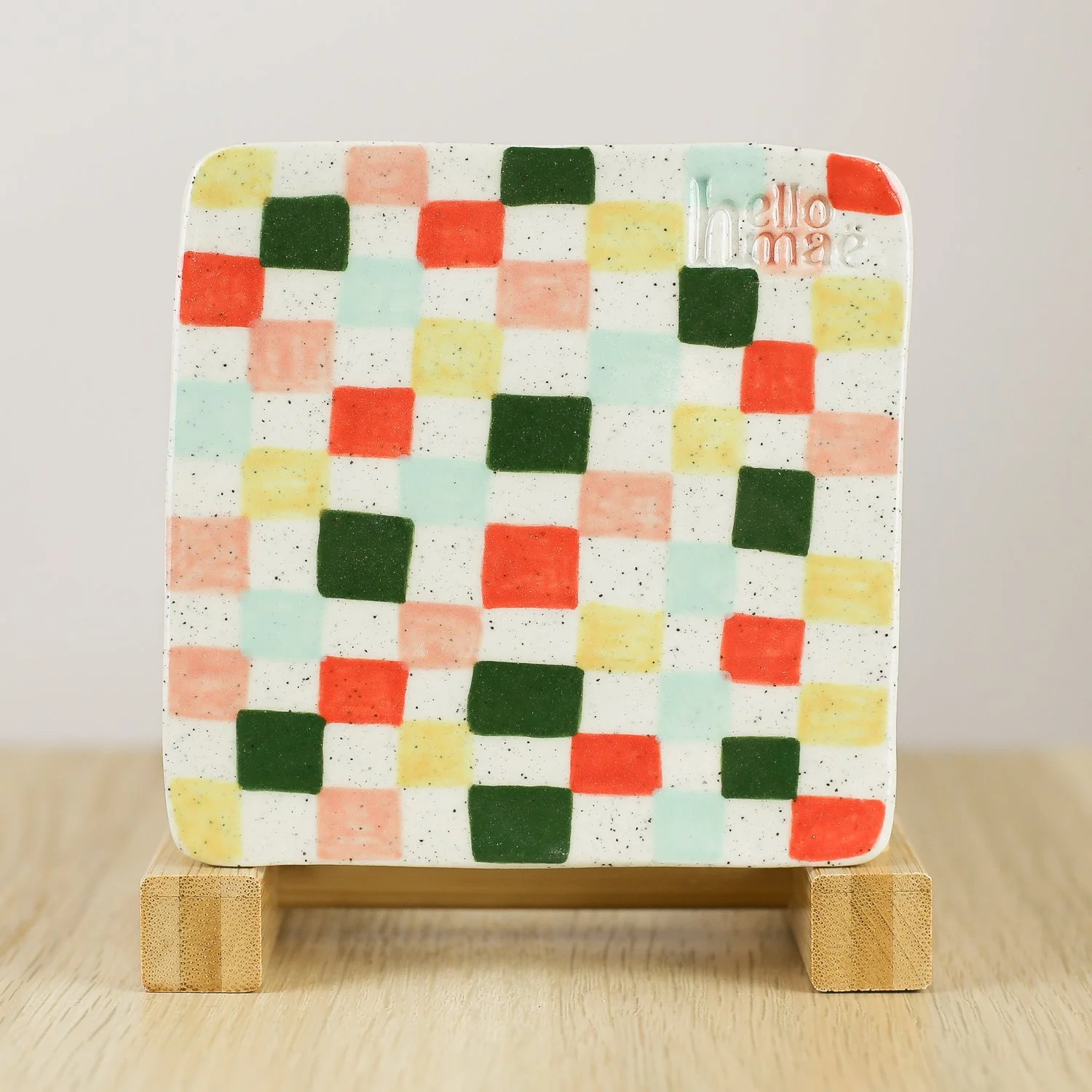 Handmade ceramic coaster with colourful check pattern in red pink yellow and blue and cork backing, 11cm by hellomae